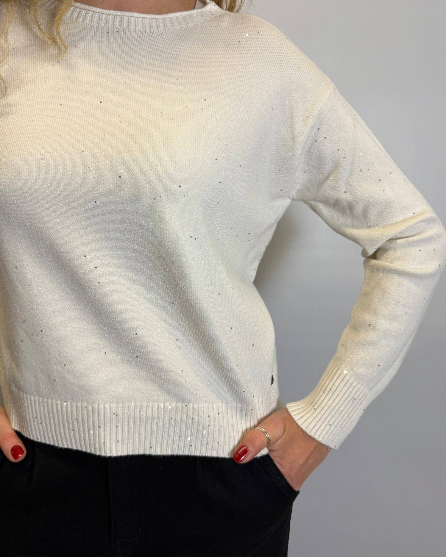 White sweater worn by a person with a plain background