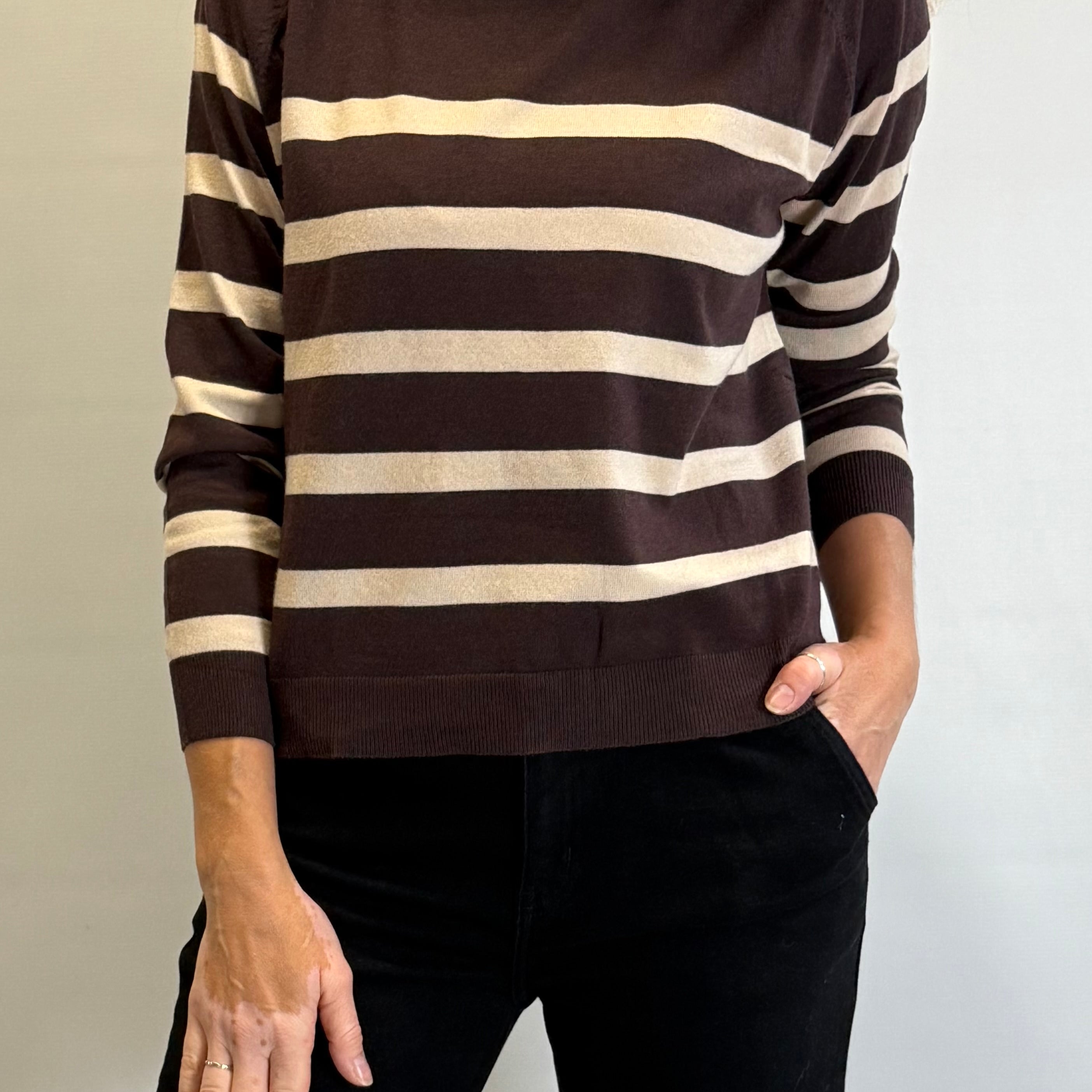 Person wearing a brown and beige striped sweater against a plain background