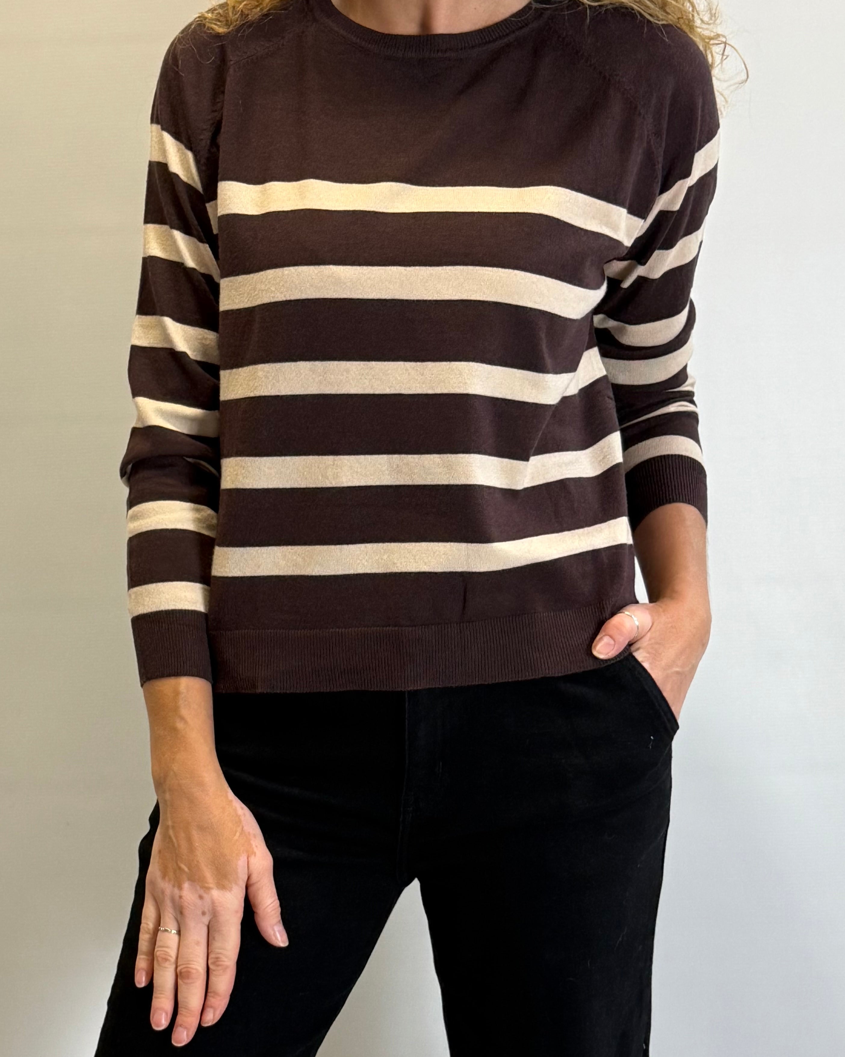 Person wearing a brown and beige striped sweater against a plain background
