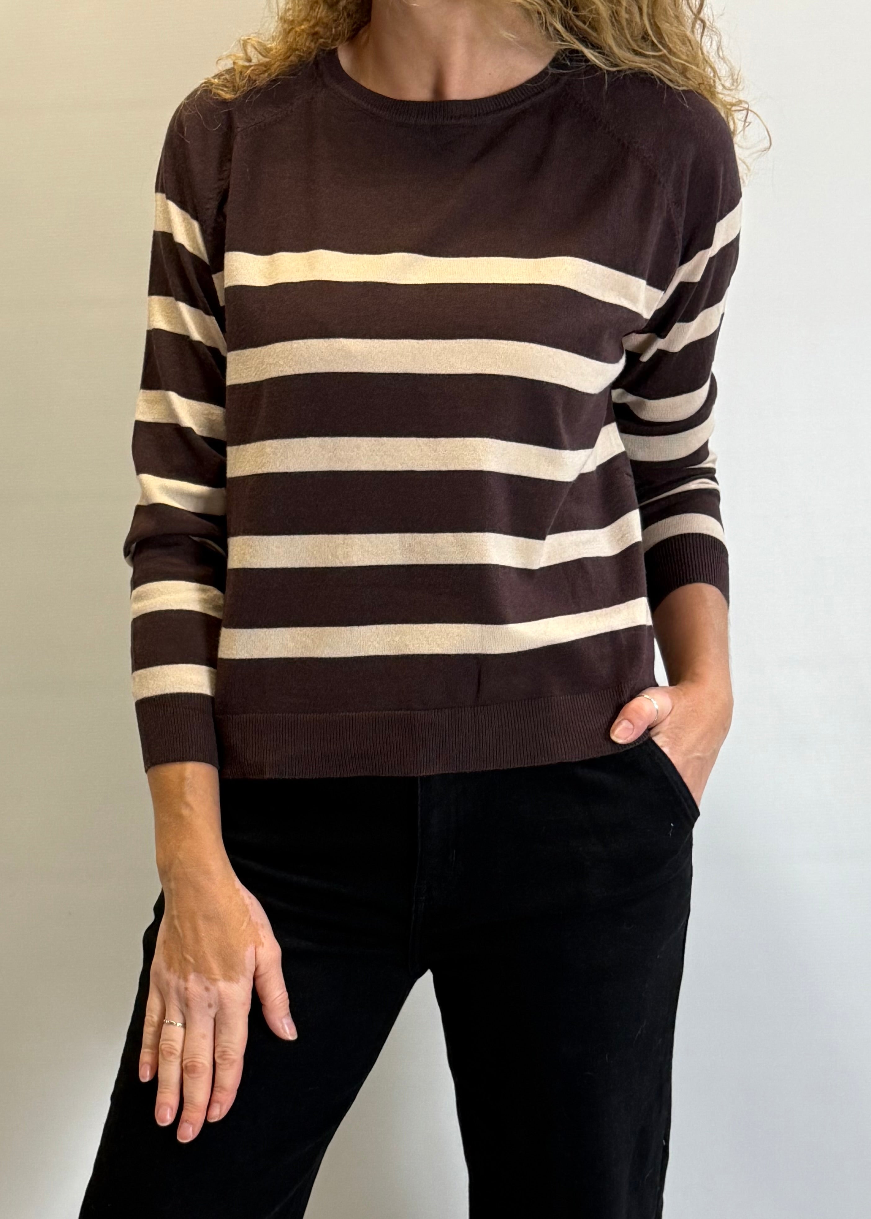 Person wearing a brown and beige striped sweater against a plain background