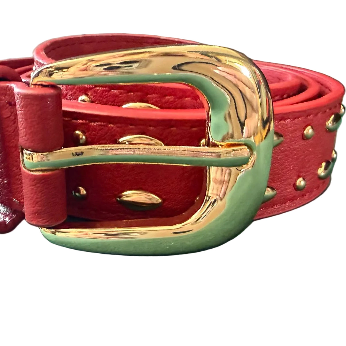 Red leather belt with gold buckle on a green surface