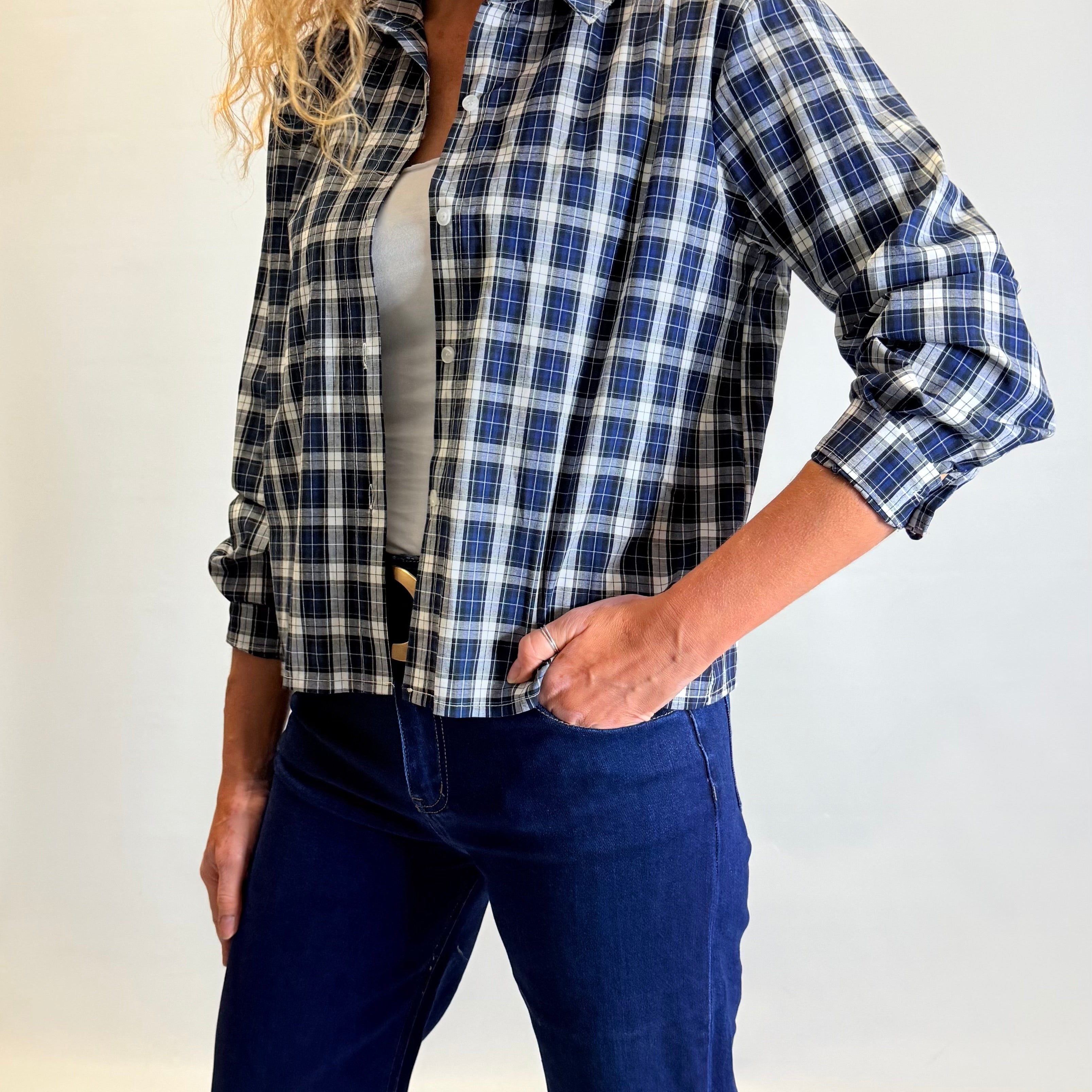 Woman wearing a blue and black plaid shirt with a plain background