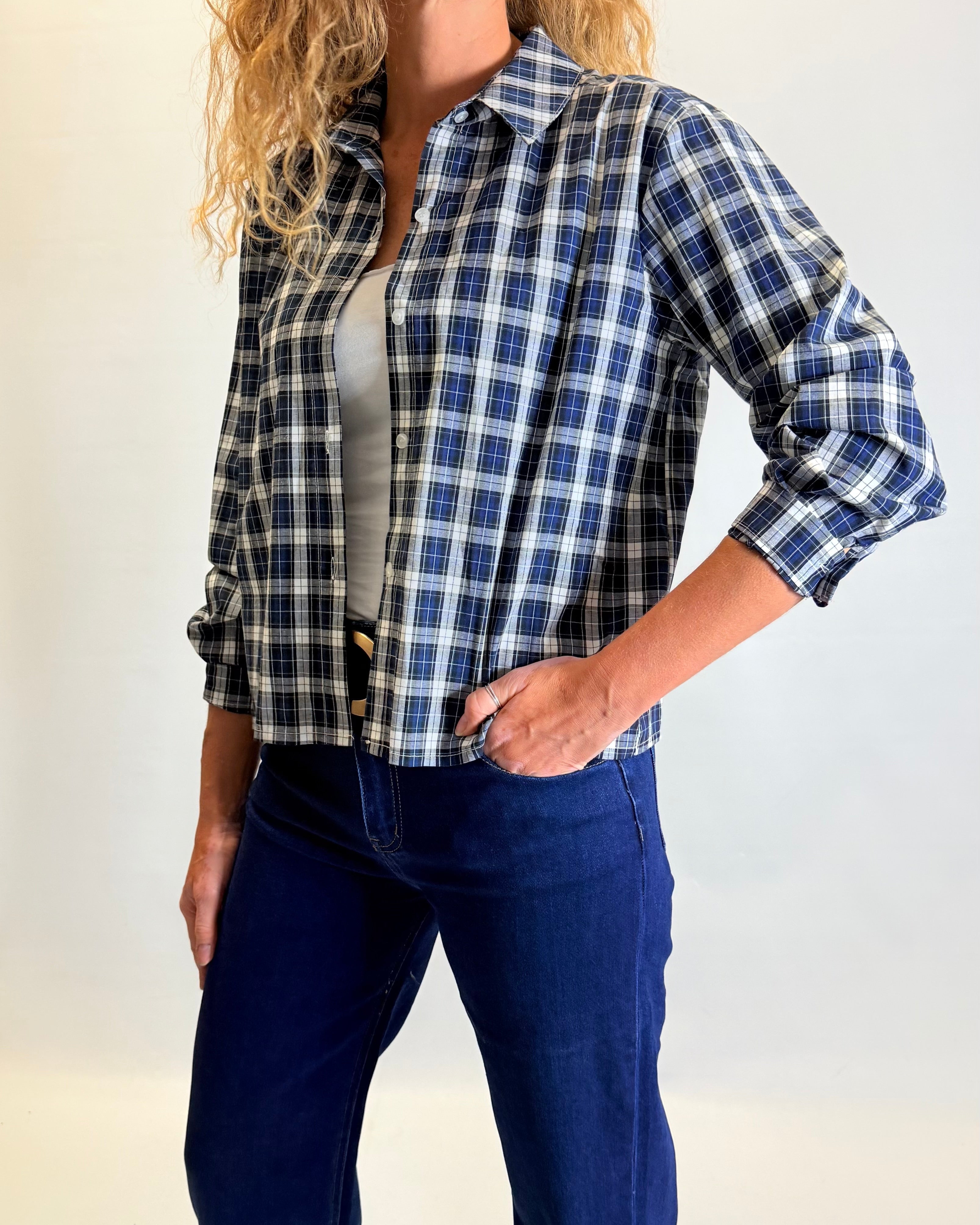 Woman wearing a blue and black plaid shirt with a plain background