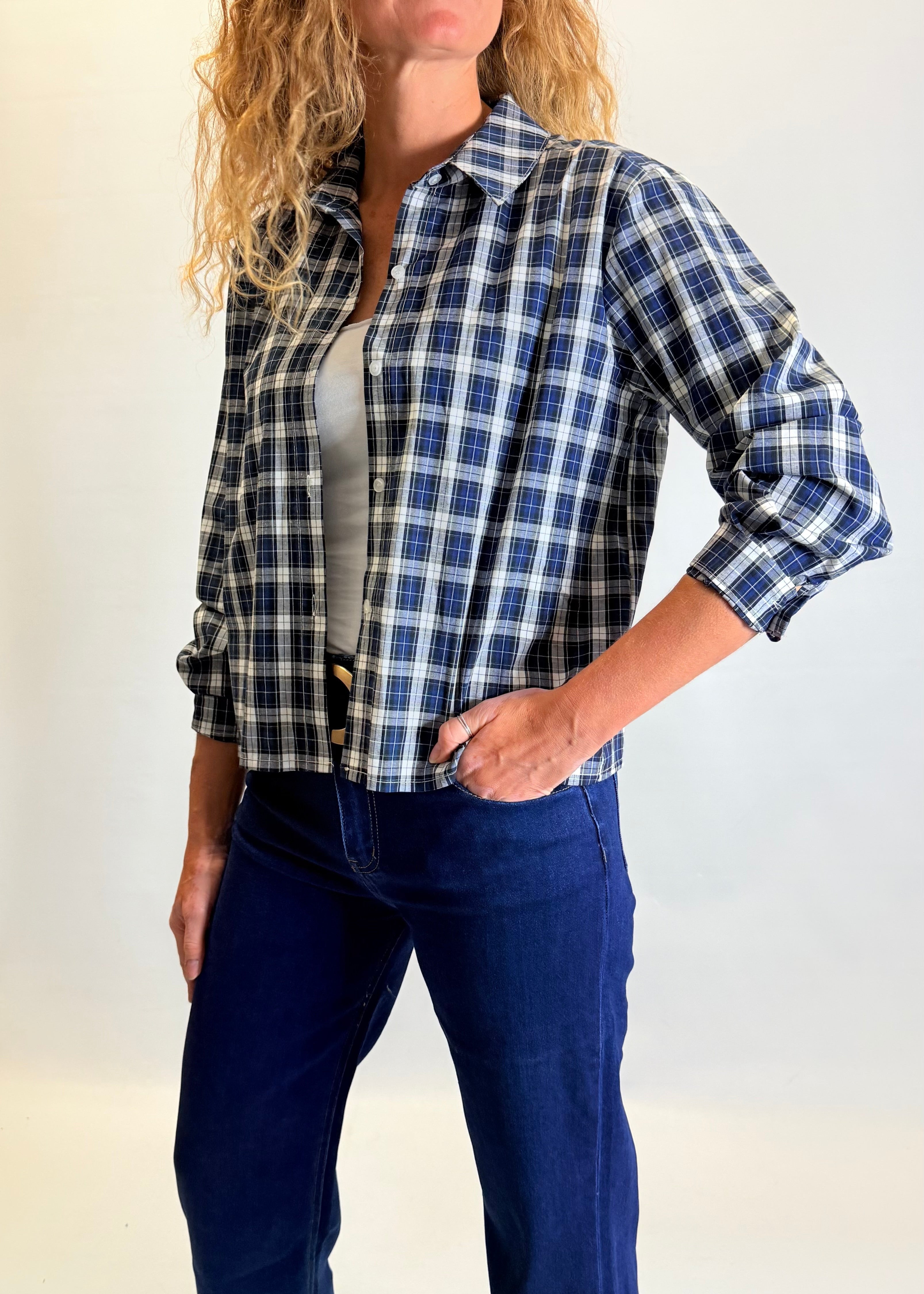 Woman wearing a blue and black plaid shirt with a plain background