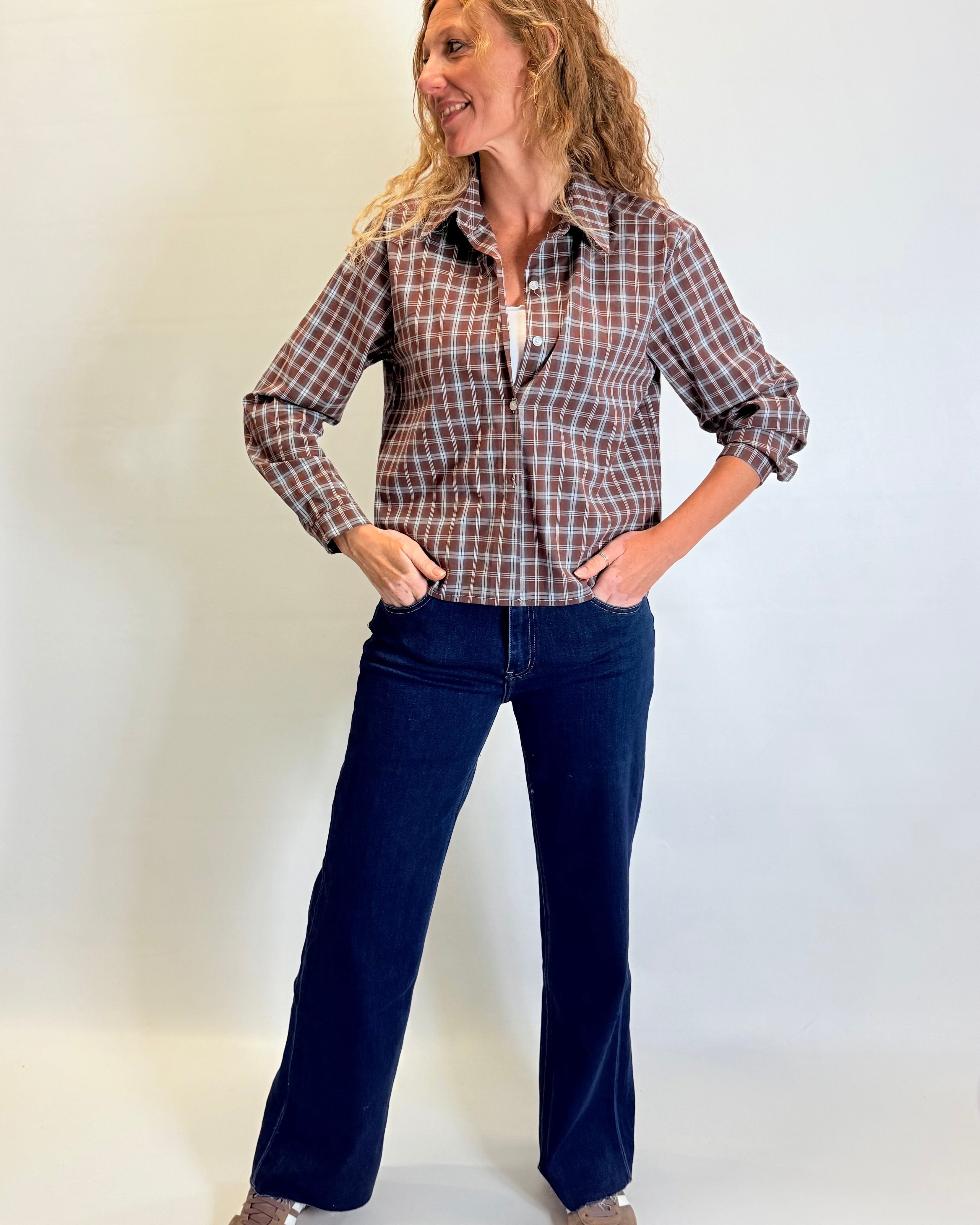 Woman wearing a plaid shirt and blue jeans against a white background