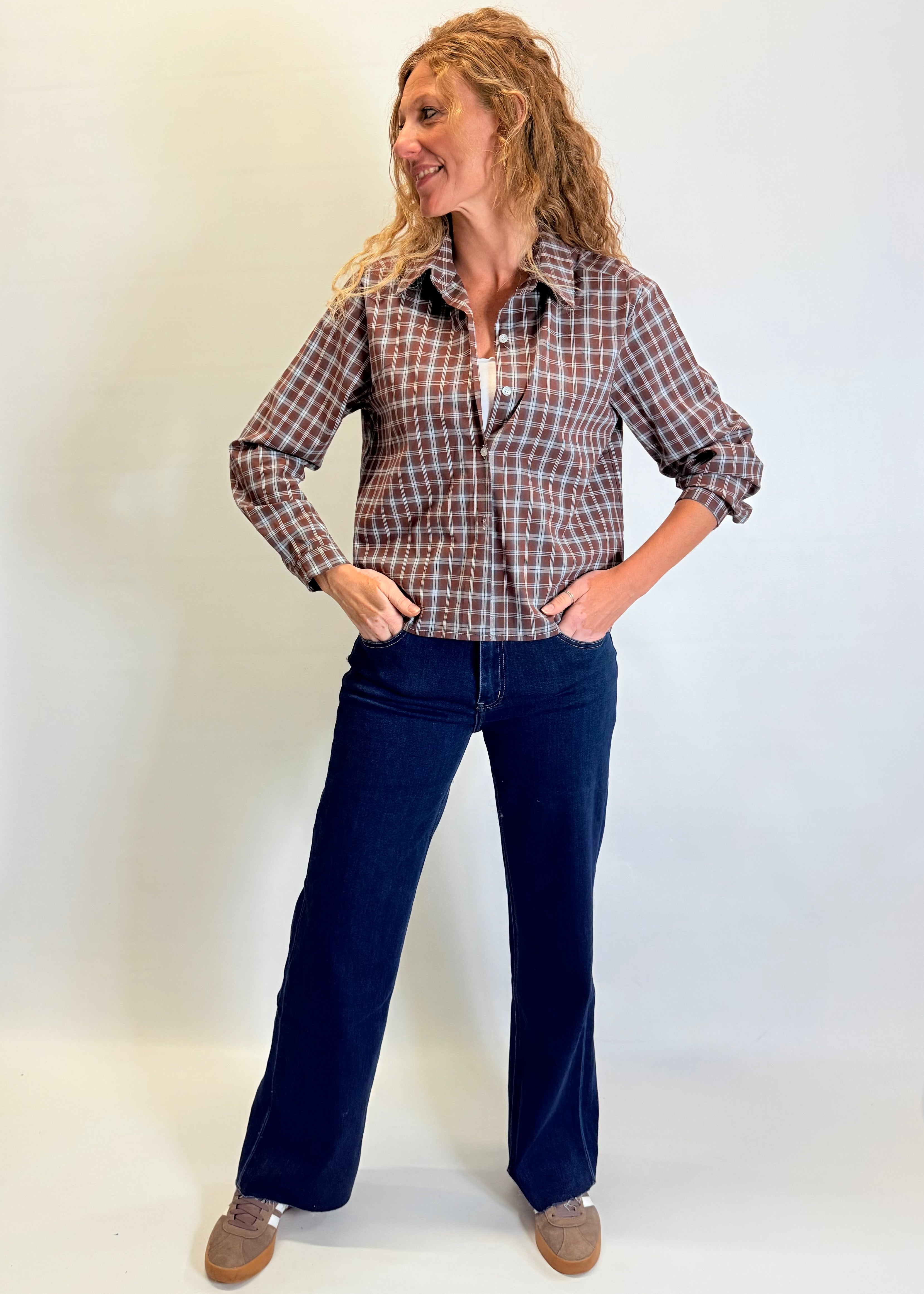 Woman wearing a plaid shirt and blue jeans against a white background