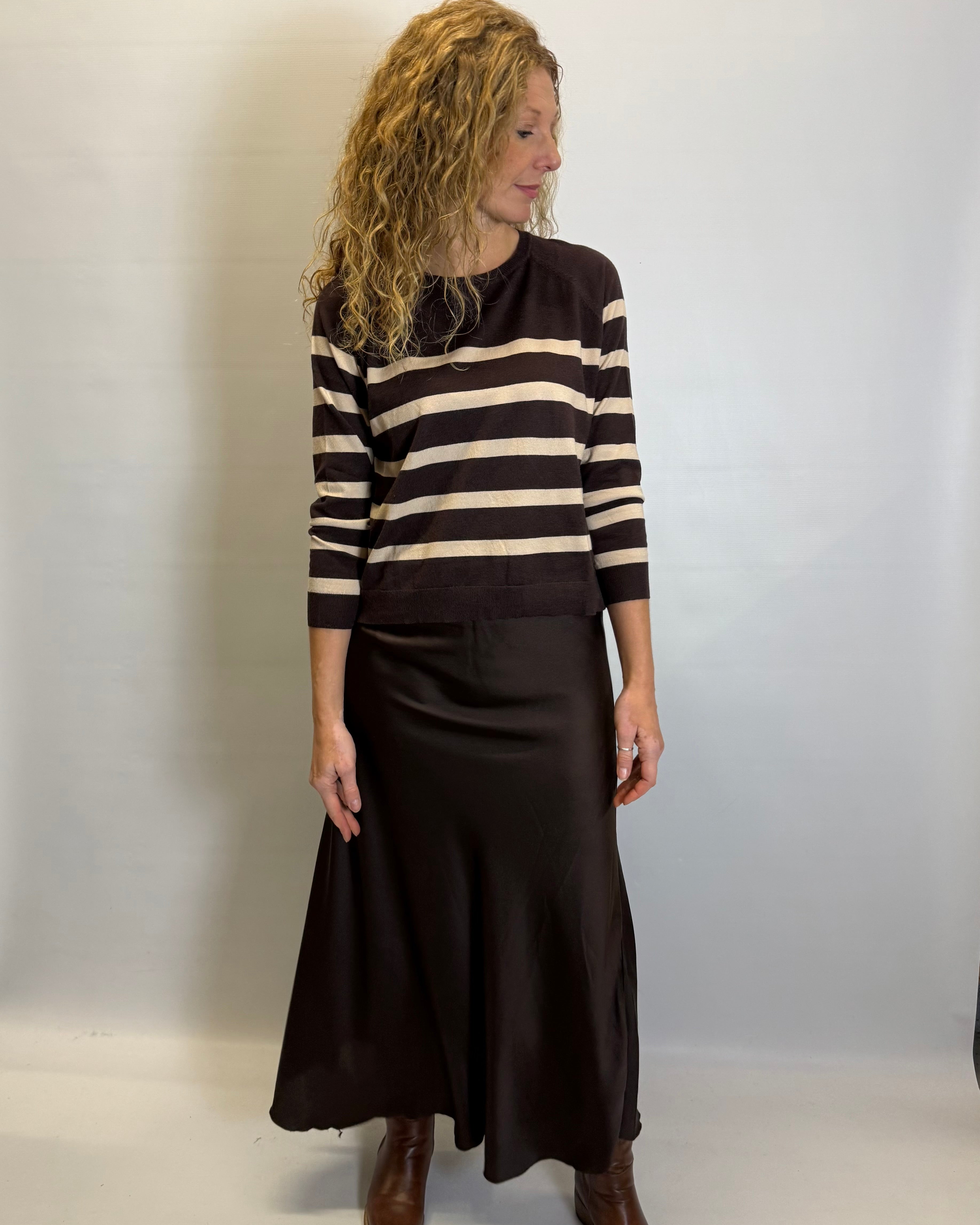 Woman wearing a black and beige striped sweater with a black skirt against a white background