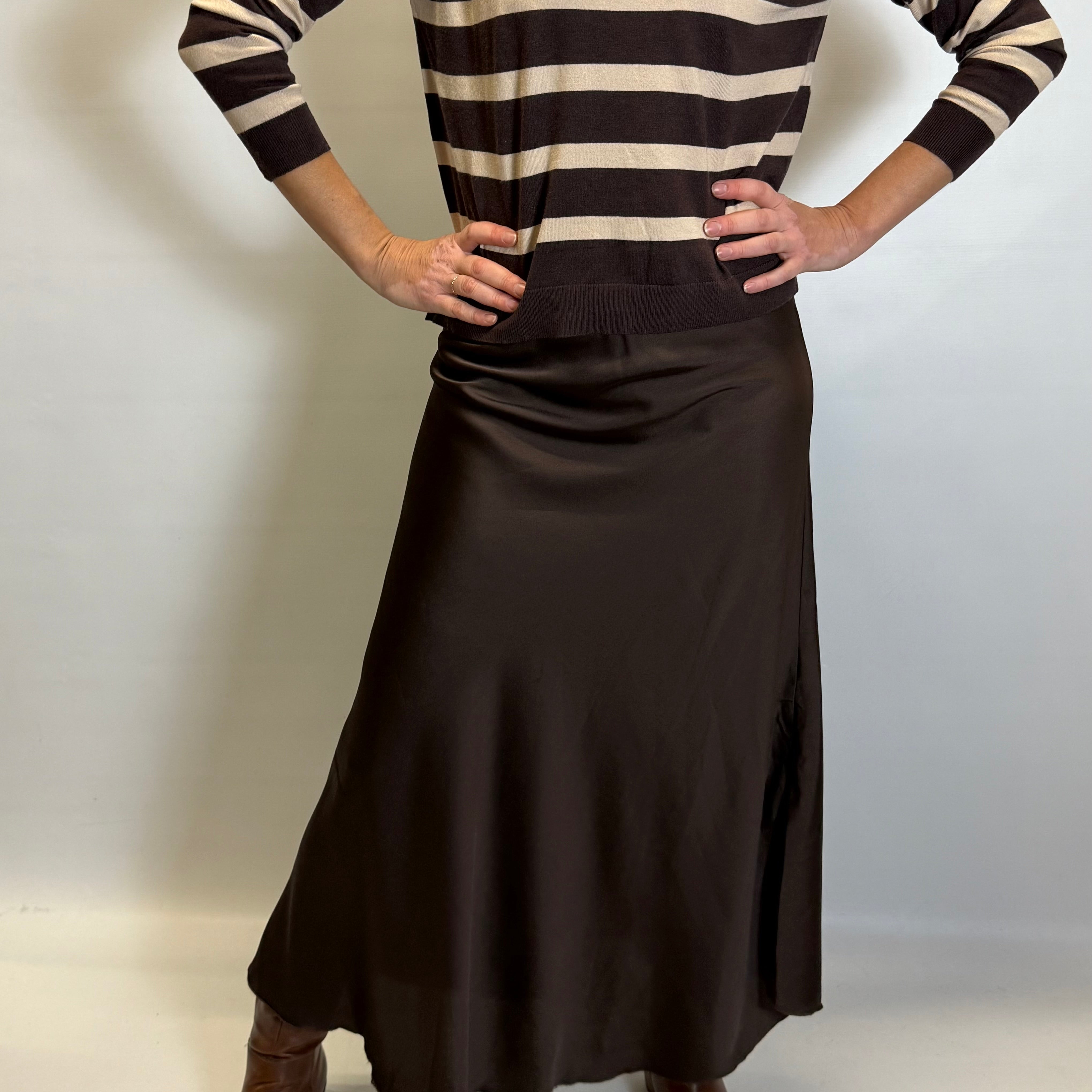 Person wearing a brown and beige striped sweater with a long brown skirt on a white background