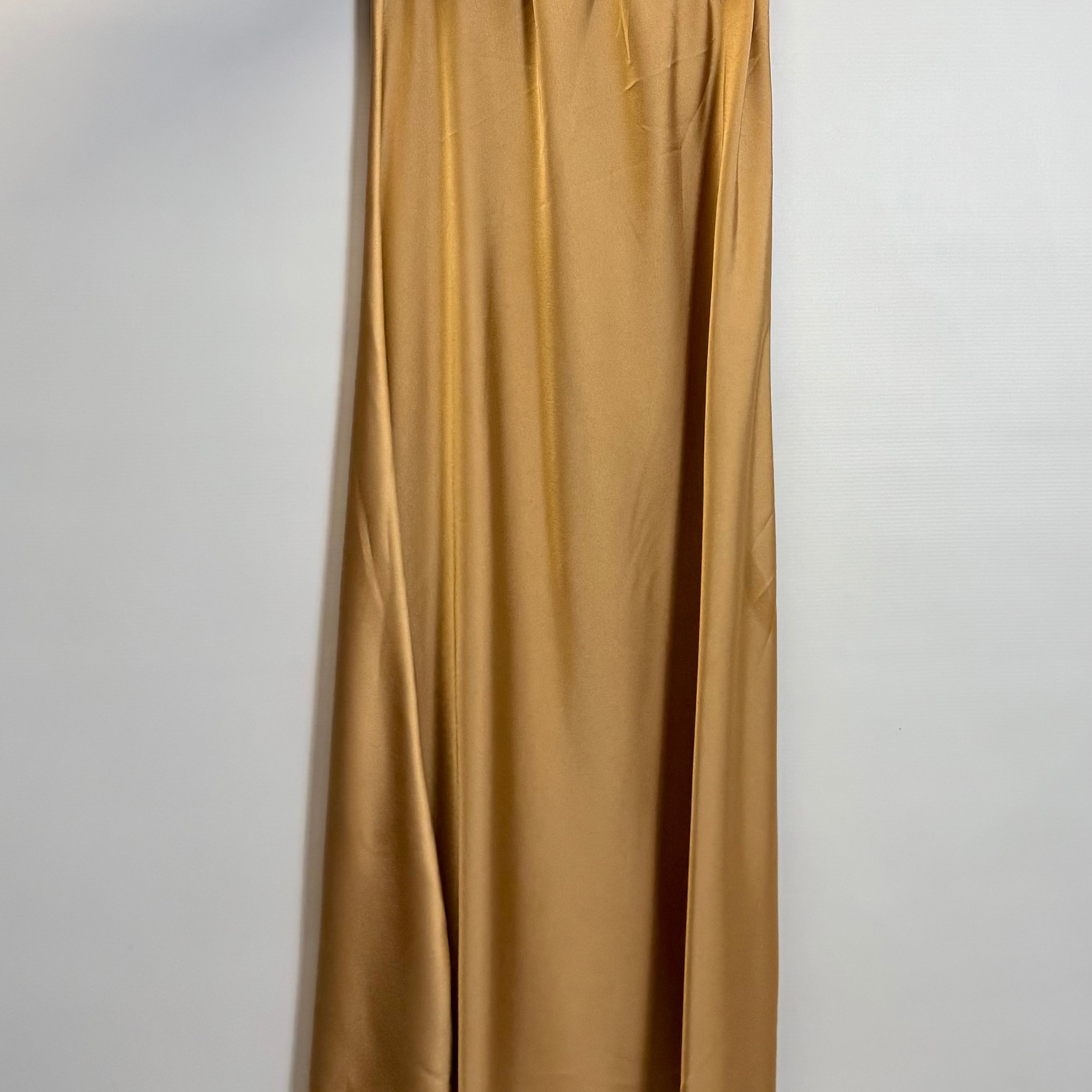 Gold satin skirt hanging on a hanger against a white background