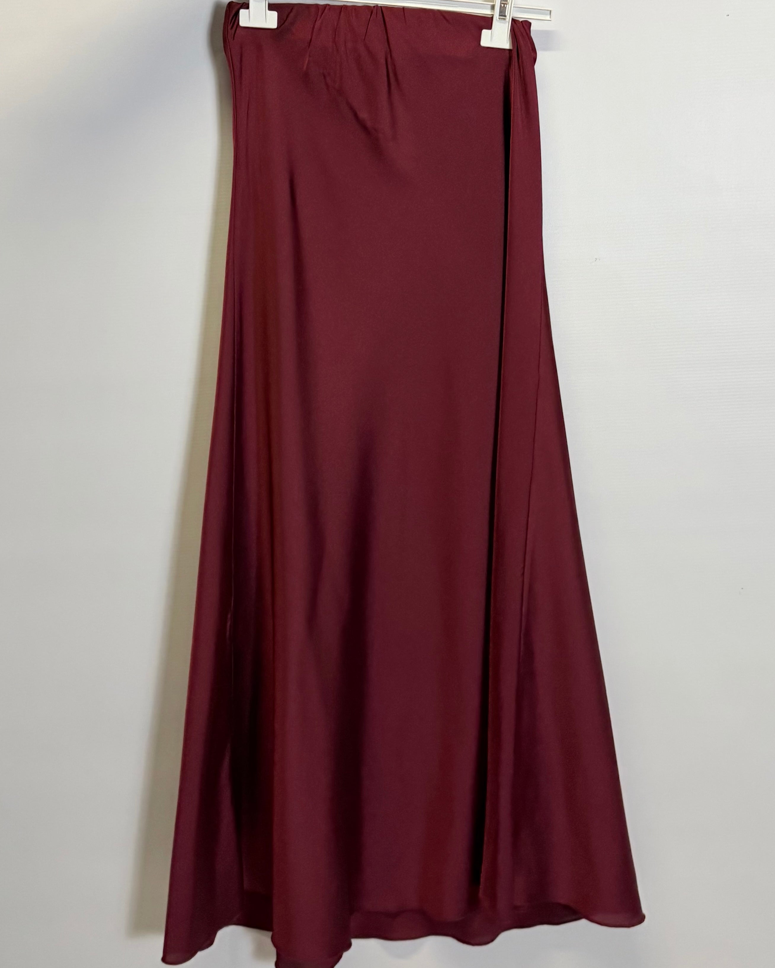 Maroon skirt on a hanger against a white background