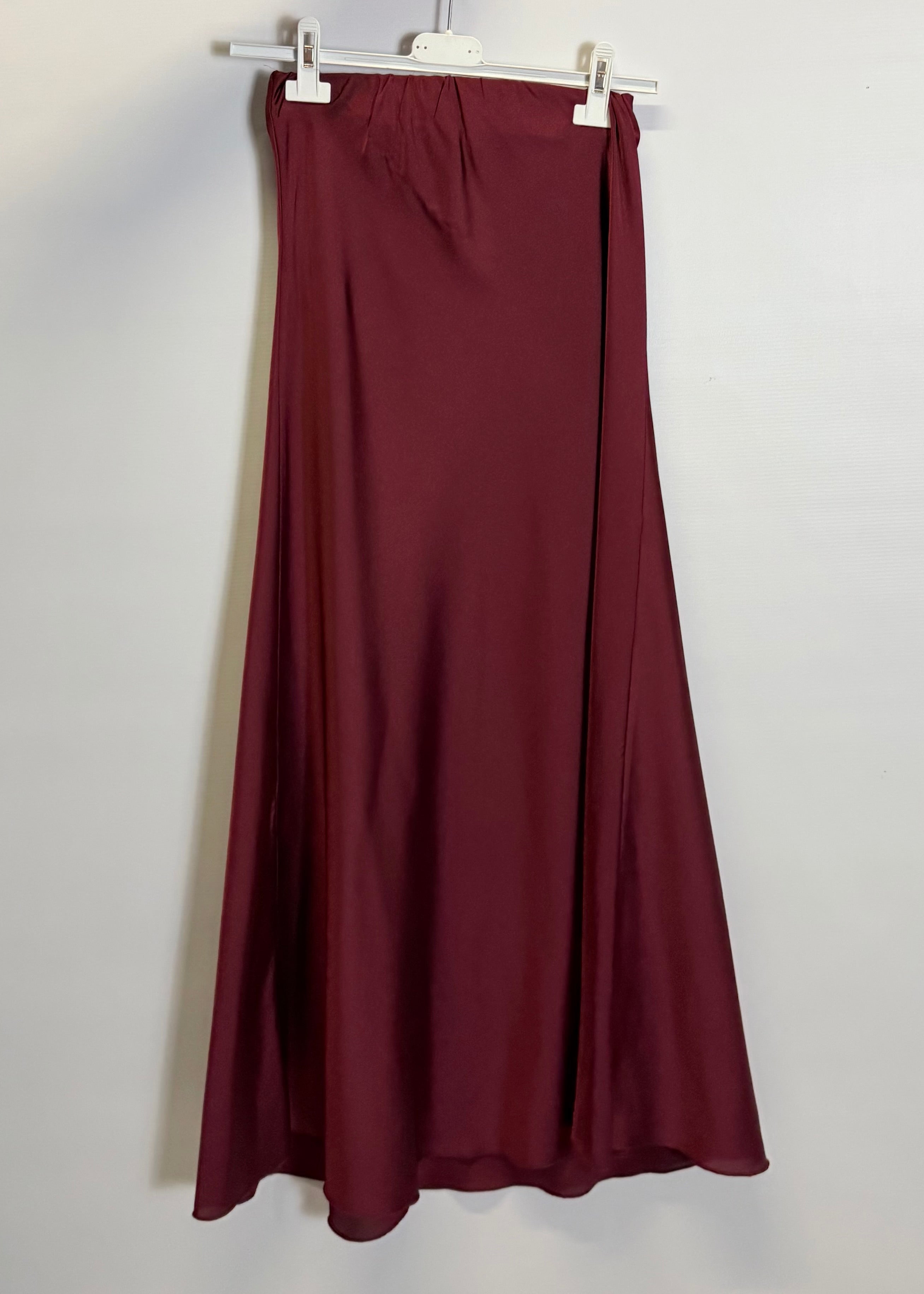 Maroon skirt on a hanger against a white background