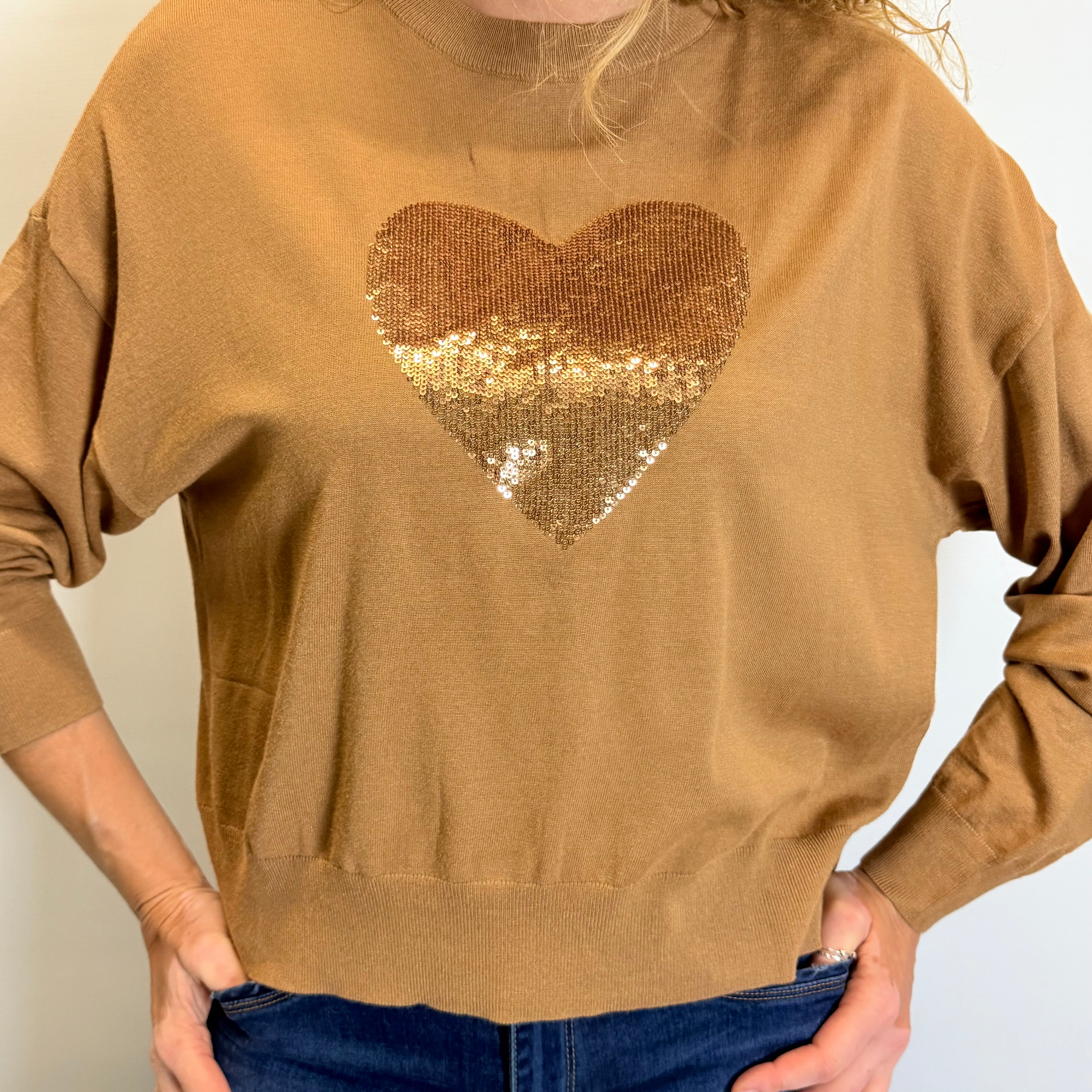 Person wearing a brown sweater with a gold sequin heart design.