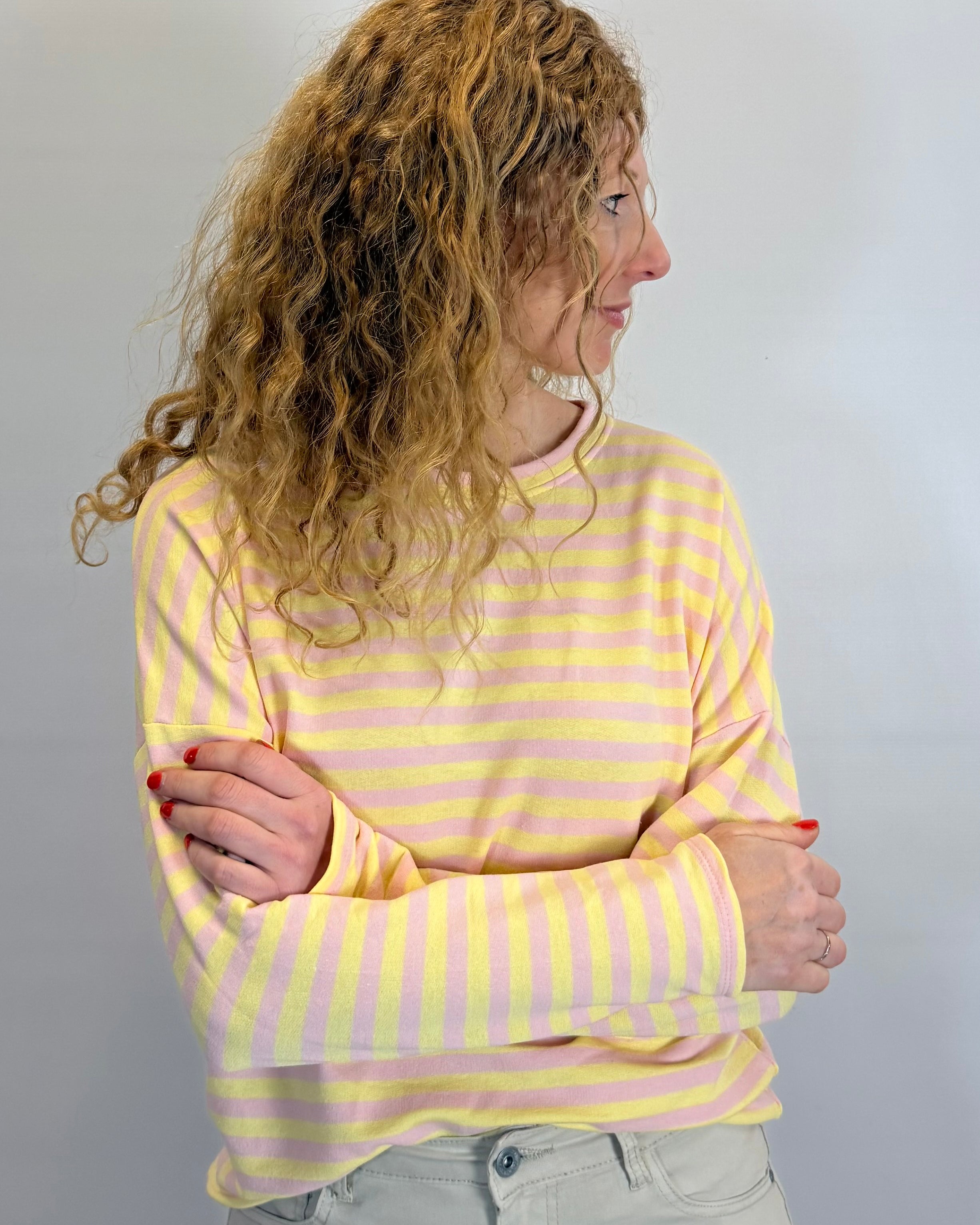 Person wearing a yellow and pink striped shirt against a plain background