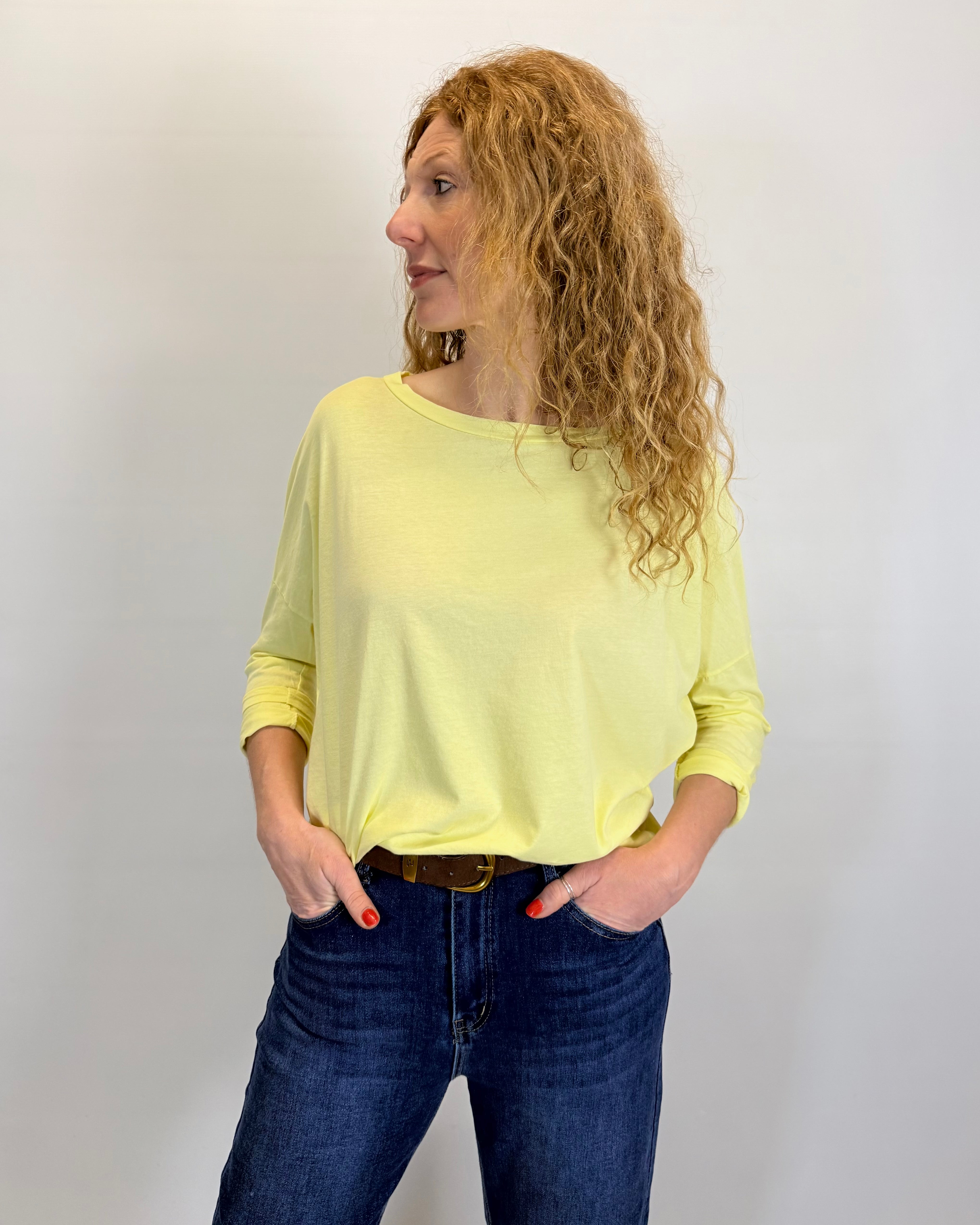Woman wearing a yellow top and blue jeans against a plain background