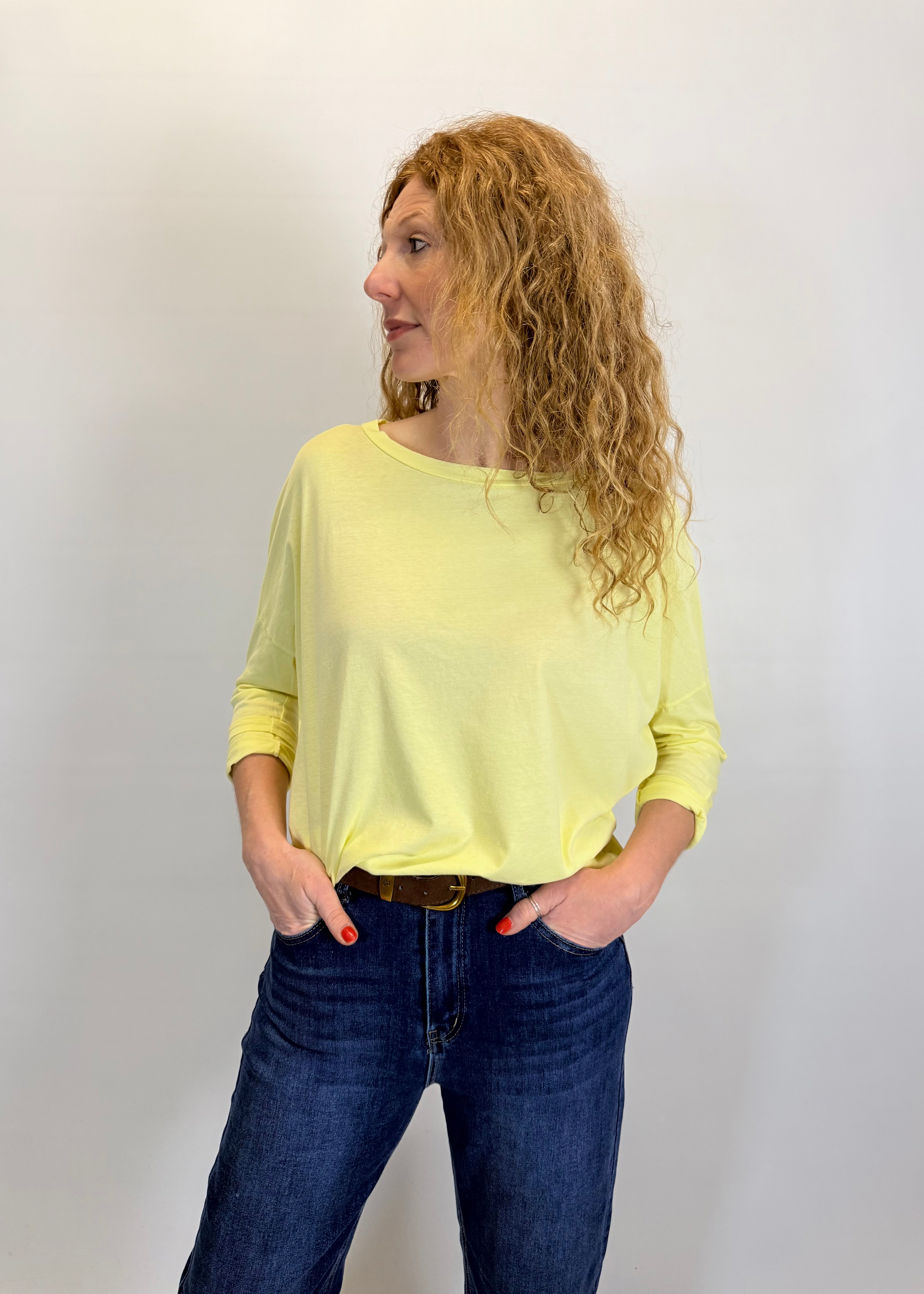 Woman wearing a yellow top and blue jeans against a plain background