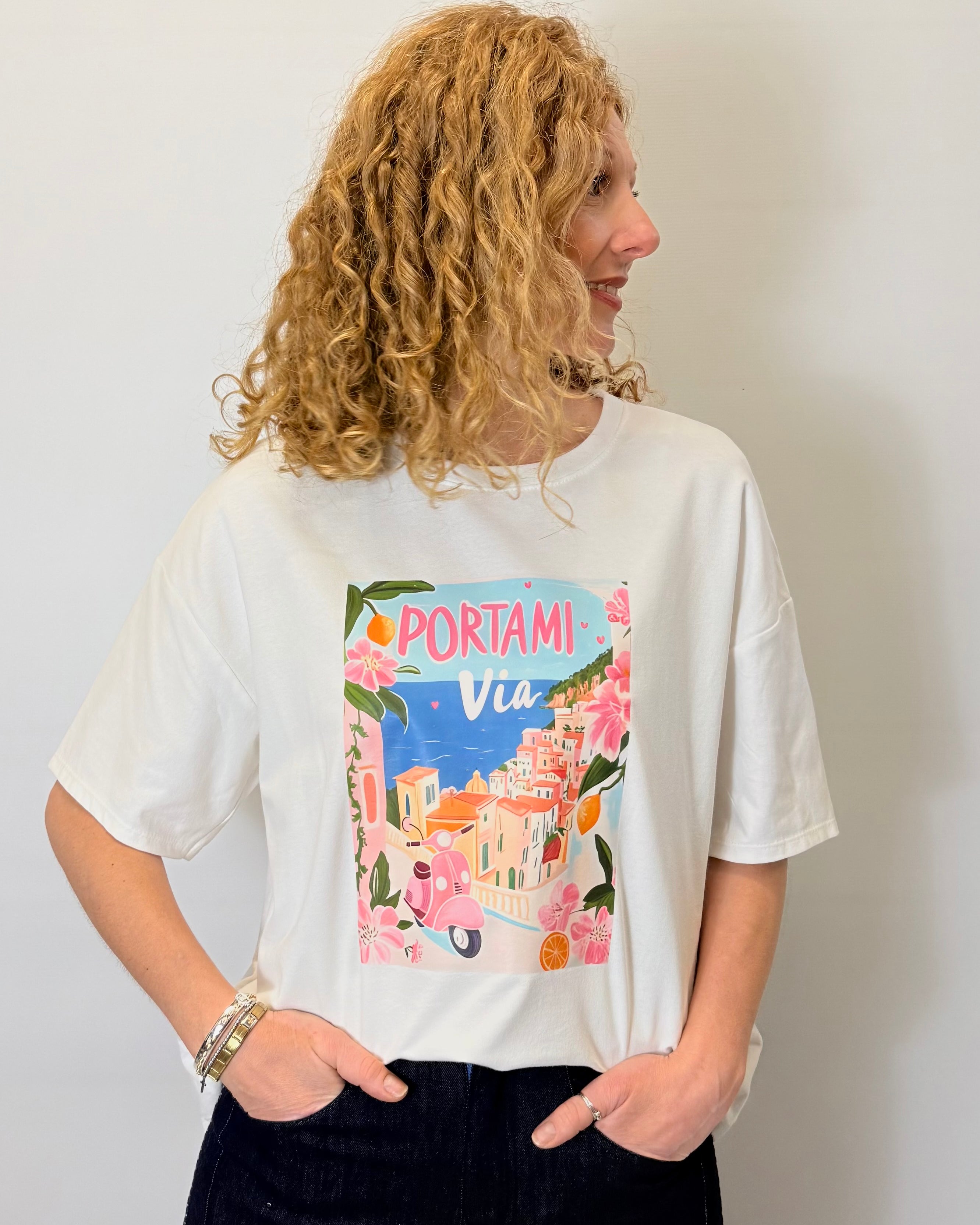 Person wearing a white t-shirt with a colorful graphic design on a plain background