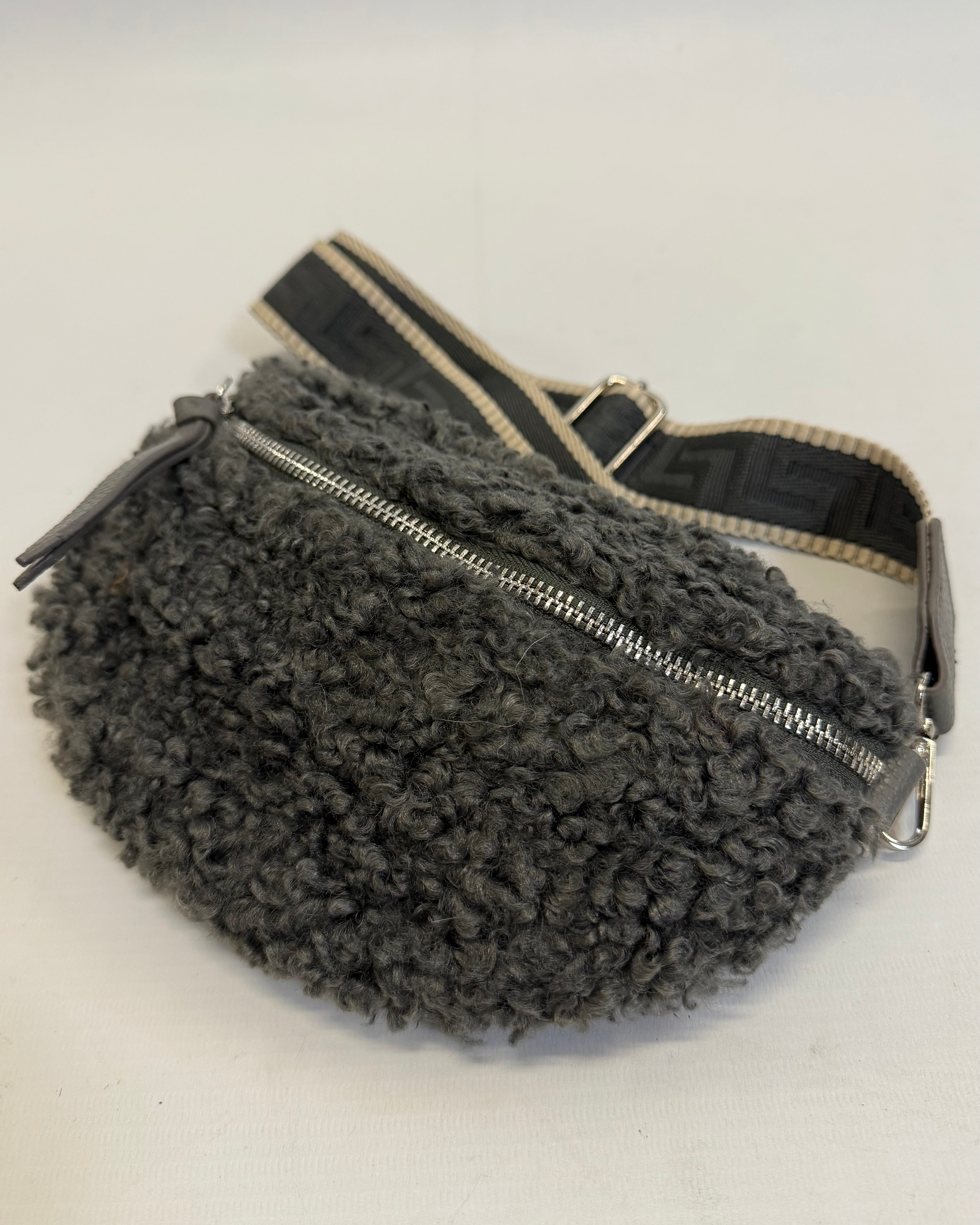 Gray fuzzy fanny pack with a zipper on a white background