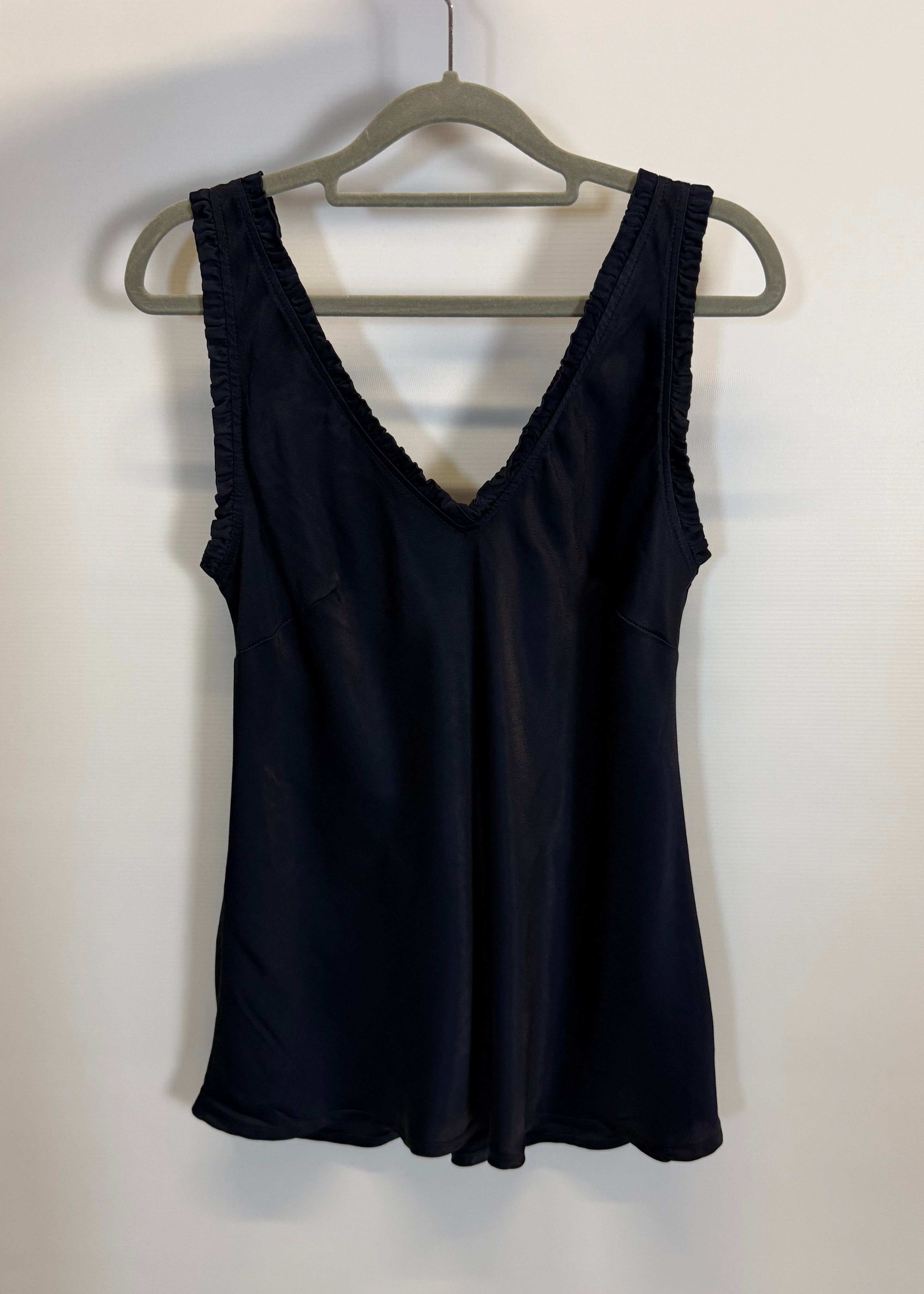 Black dress on a hanger against a white wall