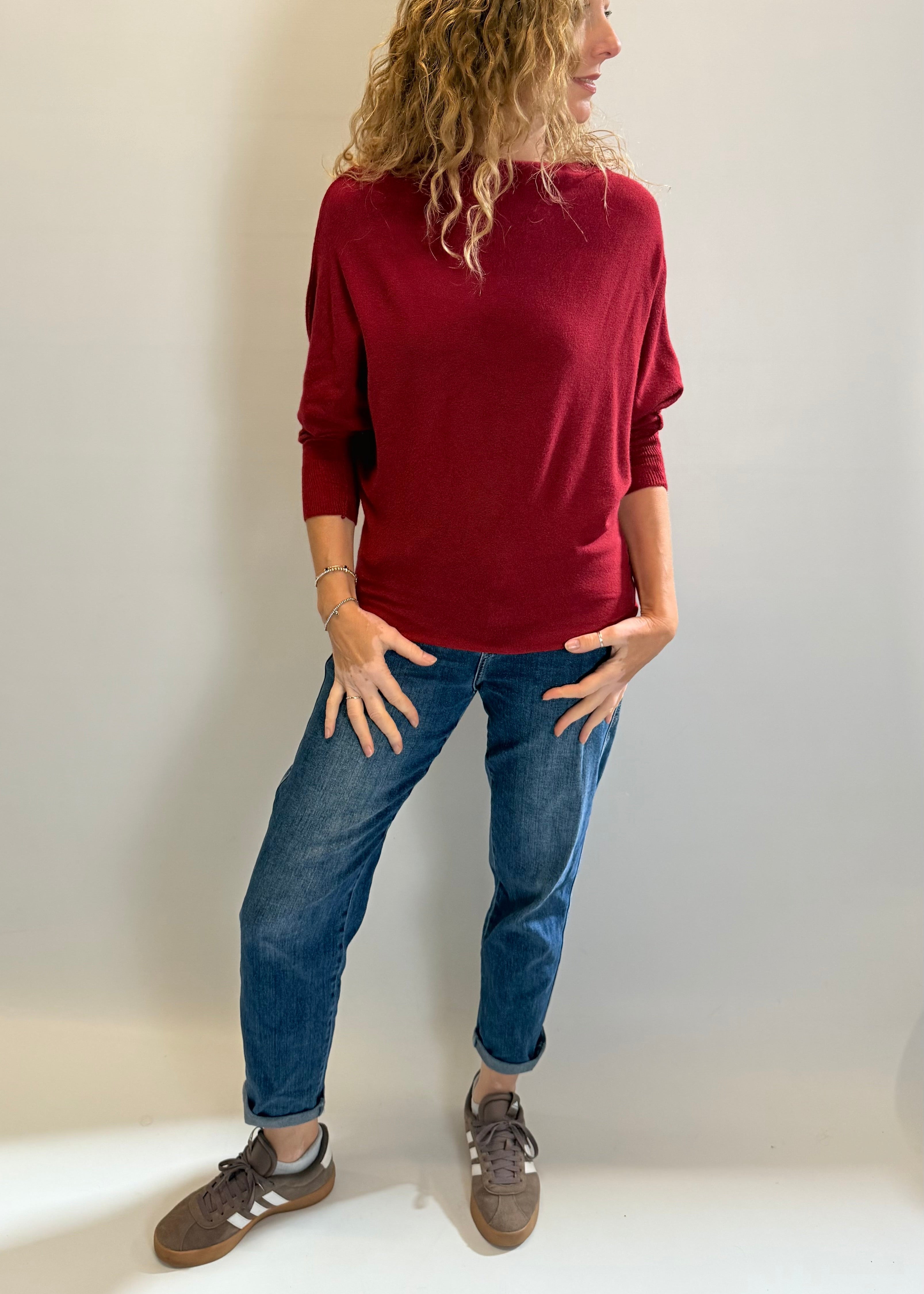Person wearing a red sweater and blue jeans against a white background