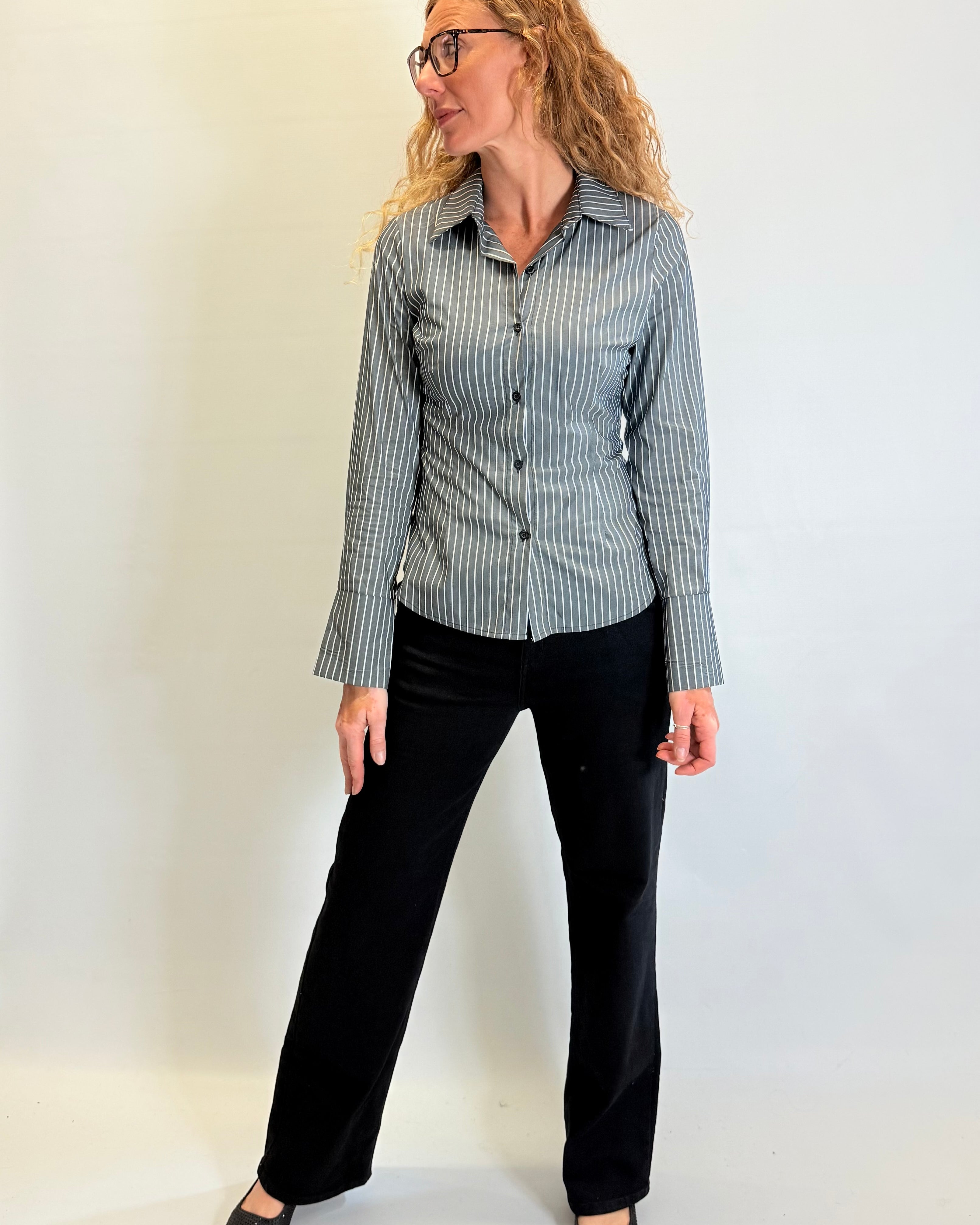 Woman wearing a striped shirt and black pants against a white background