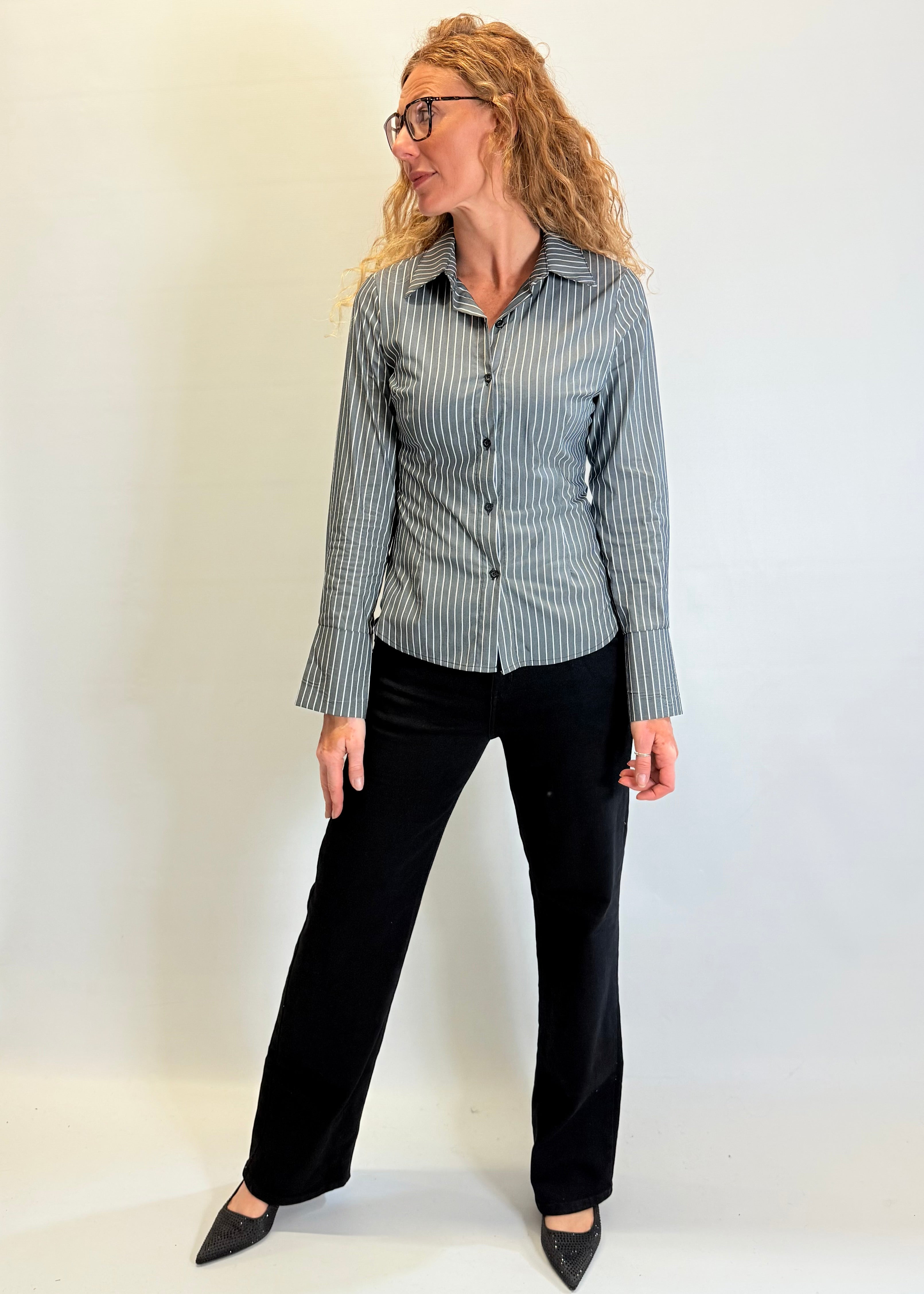 Woman wearing a striped shirt and black pants against a white background