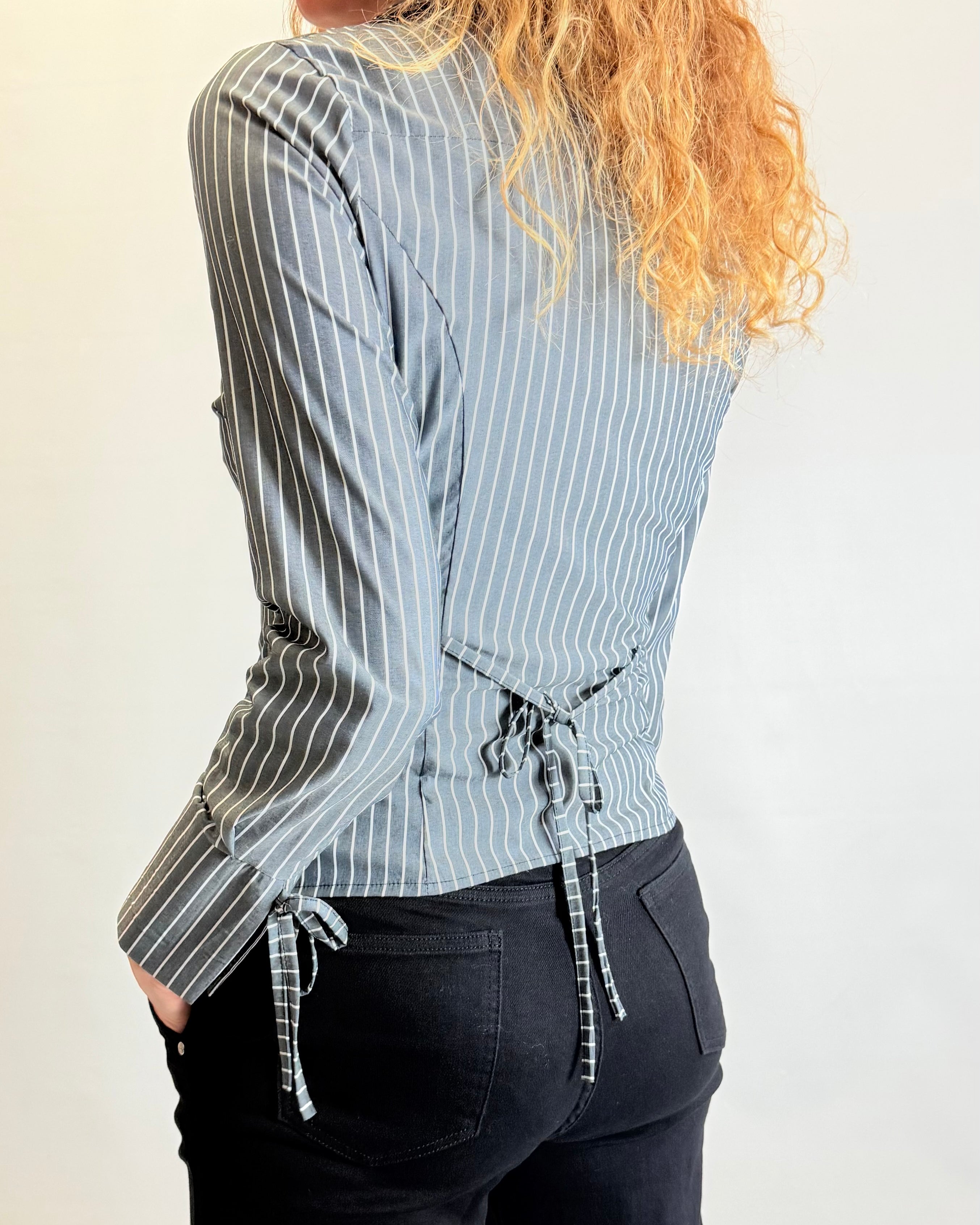 Person wearing a blue and white striped shirt with a drawstring waist, standing against a plain background.