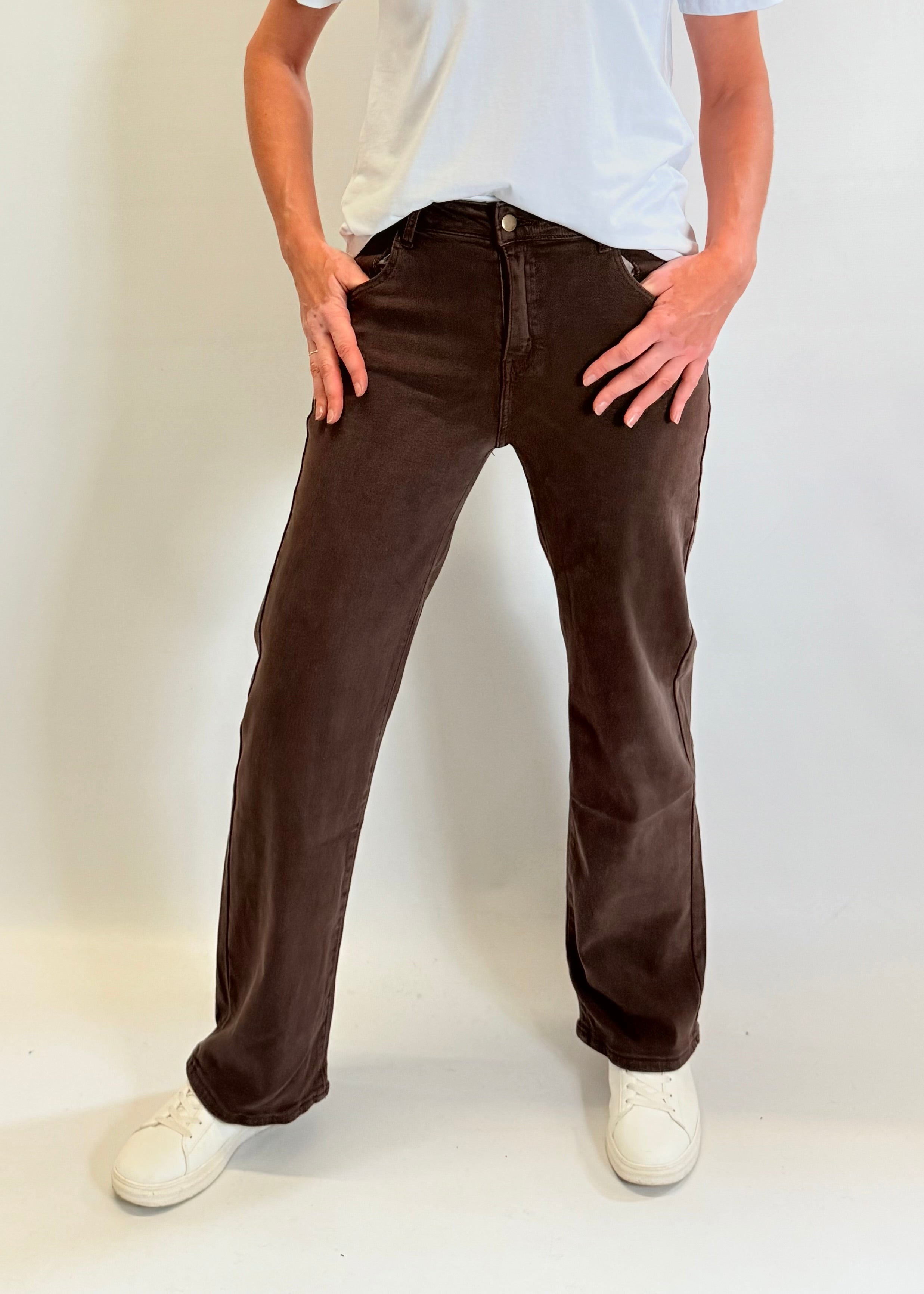 Person wearing brown pants and white shoes on a plain background