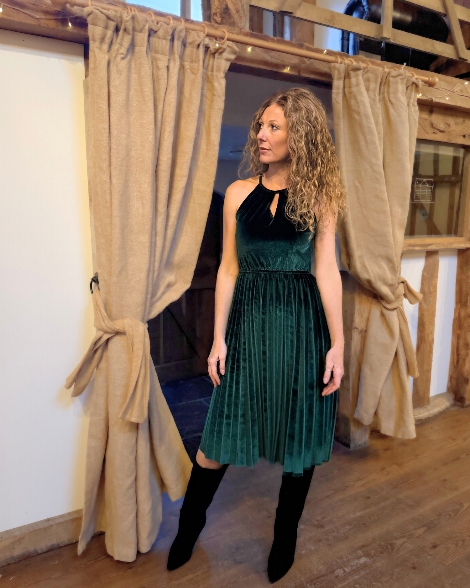 Lady wearing green velvet dress with long black boots.