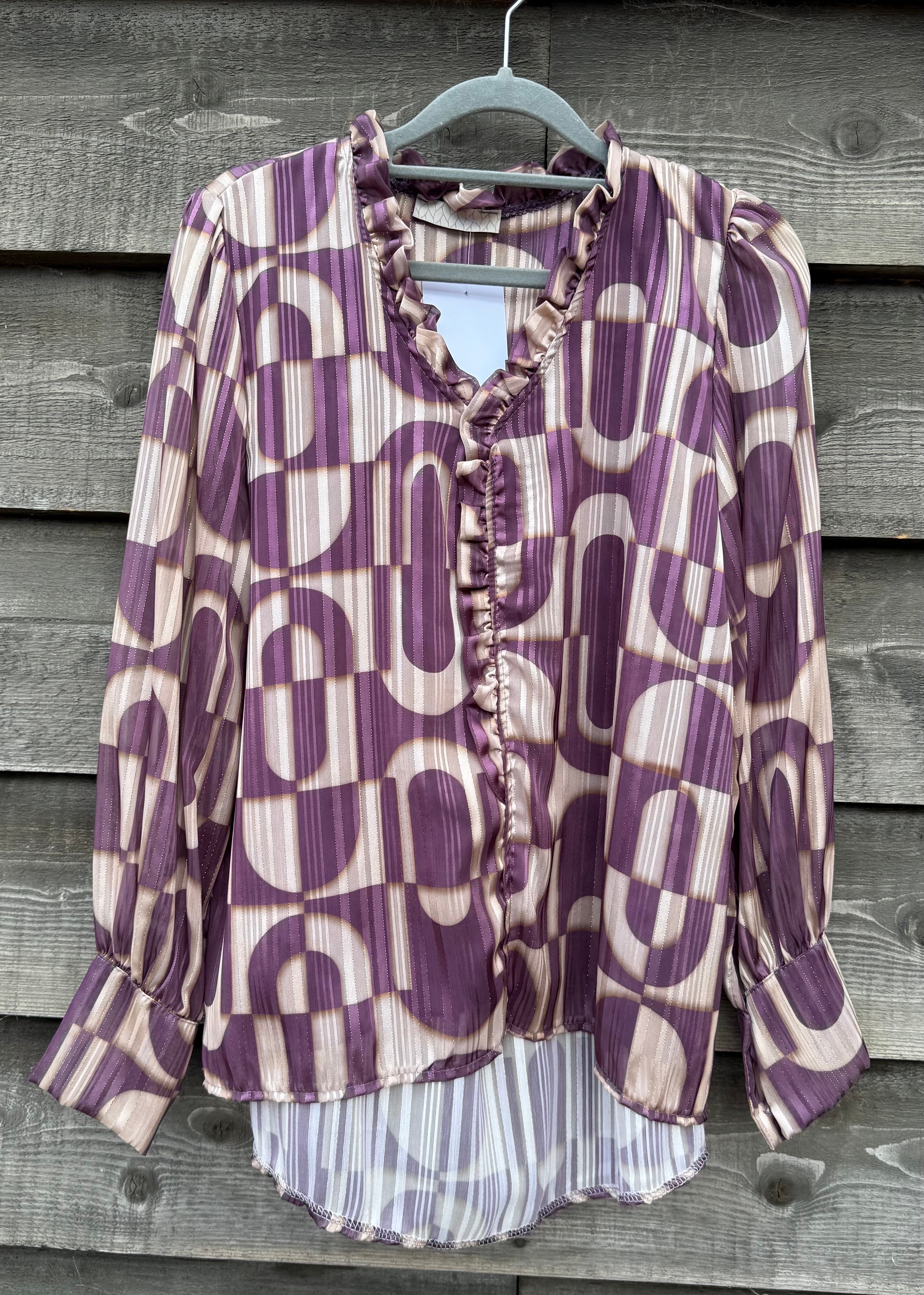 Purple and white patterned blouse on a hanger against a wooden background