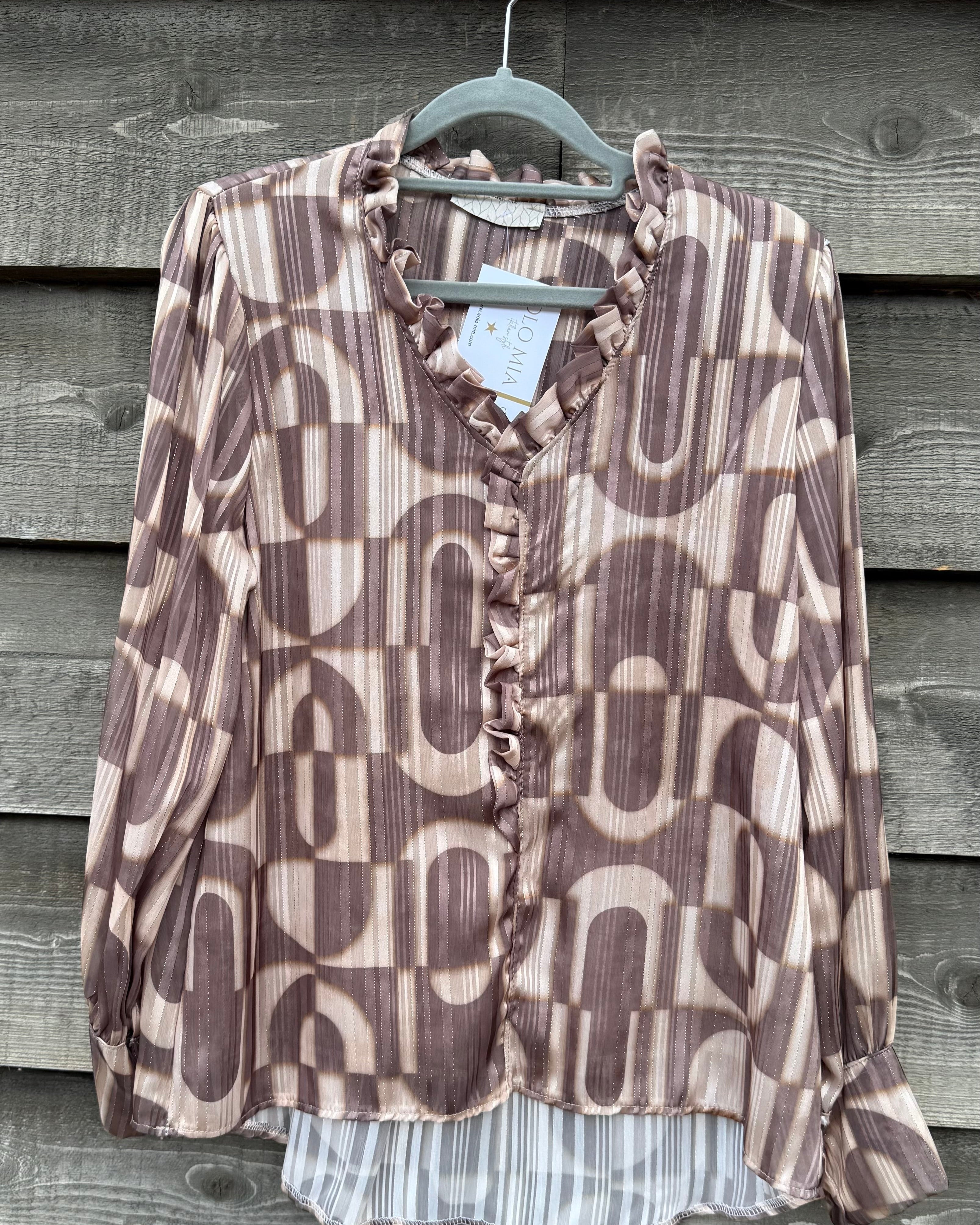 Patterned blouse on a hanger against a wooden background