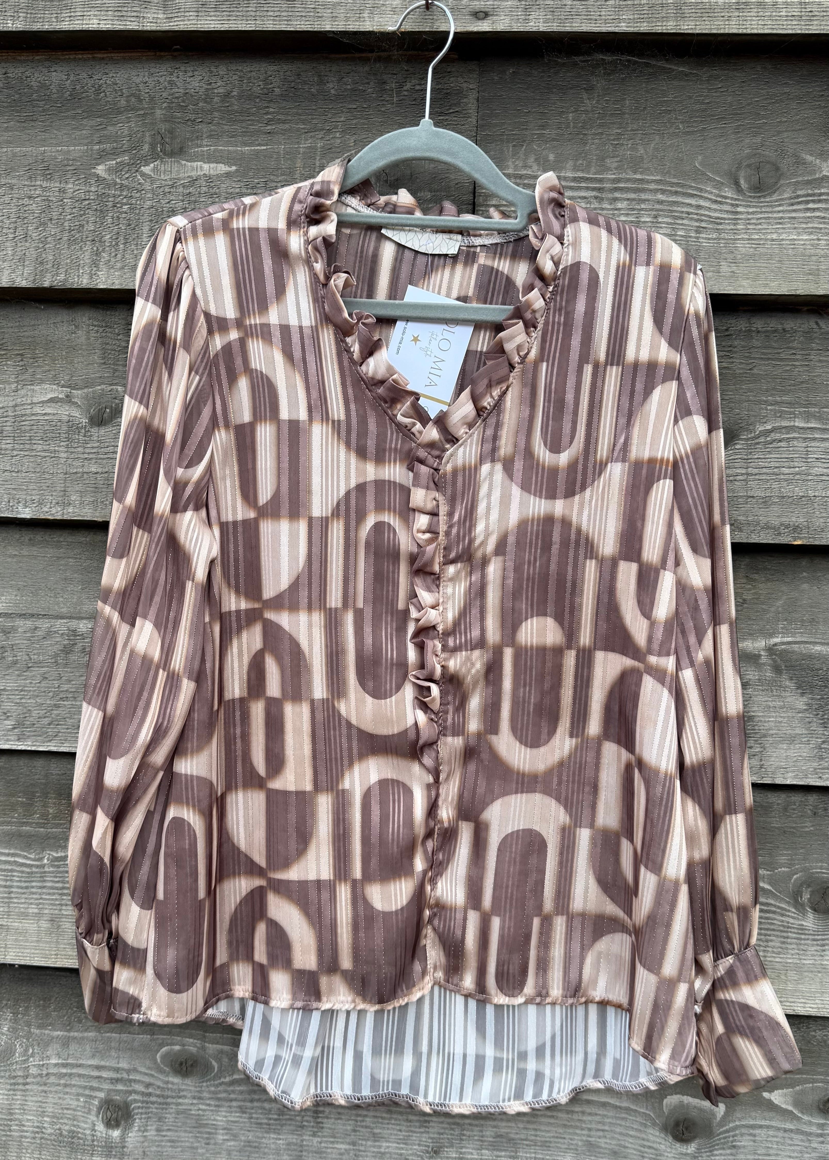 Patterned blouse on a hanger against a wooden background