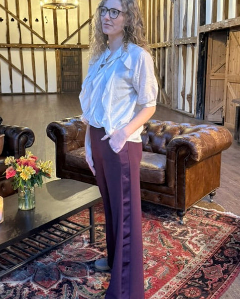 Lady wearing blouse with wide leg trousers with a satin side stripe and pockets on trousers.