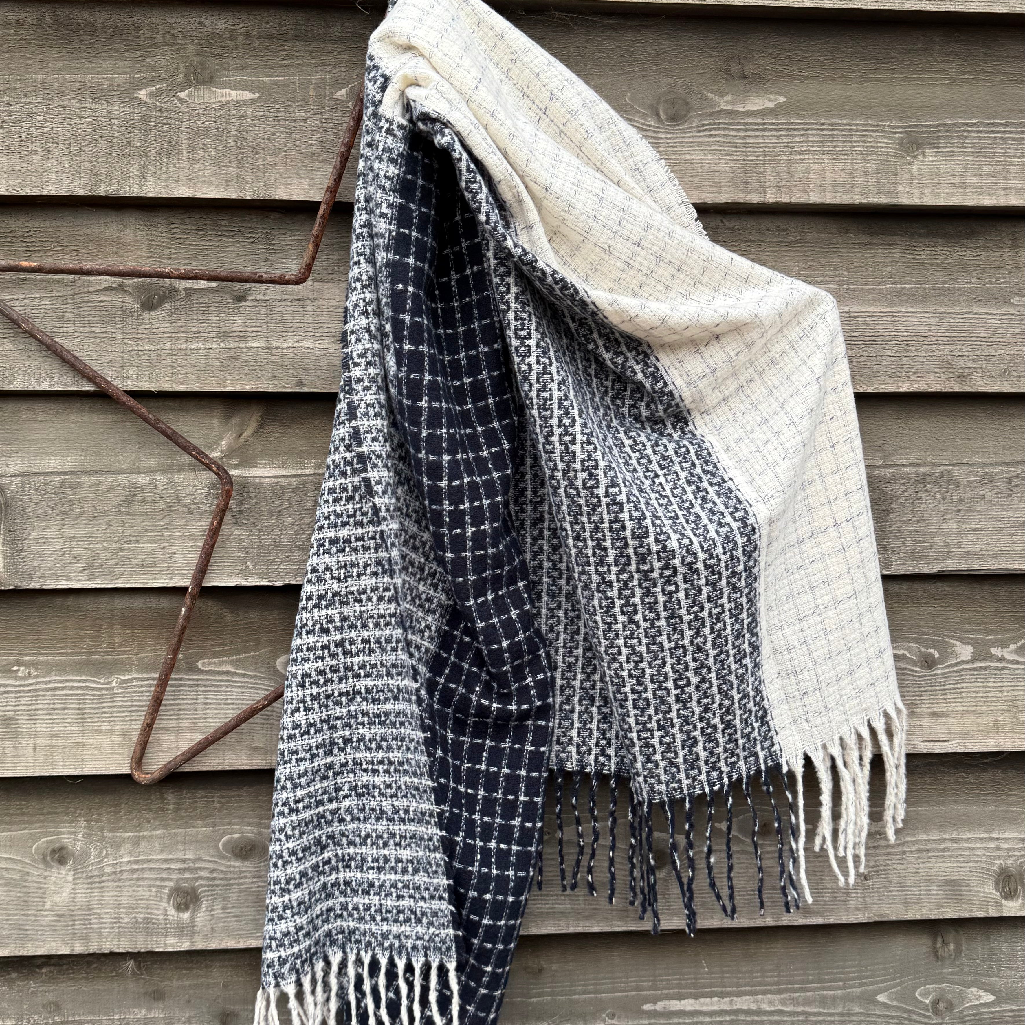 Textured blanket with fringes draped over a wooden surface