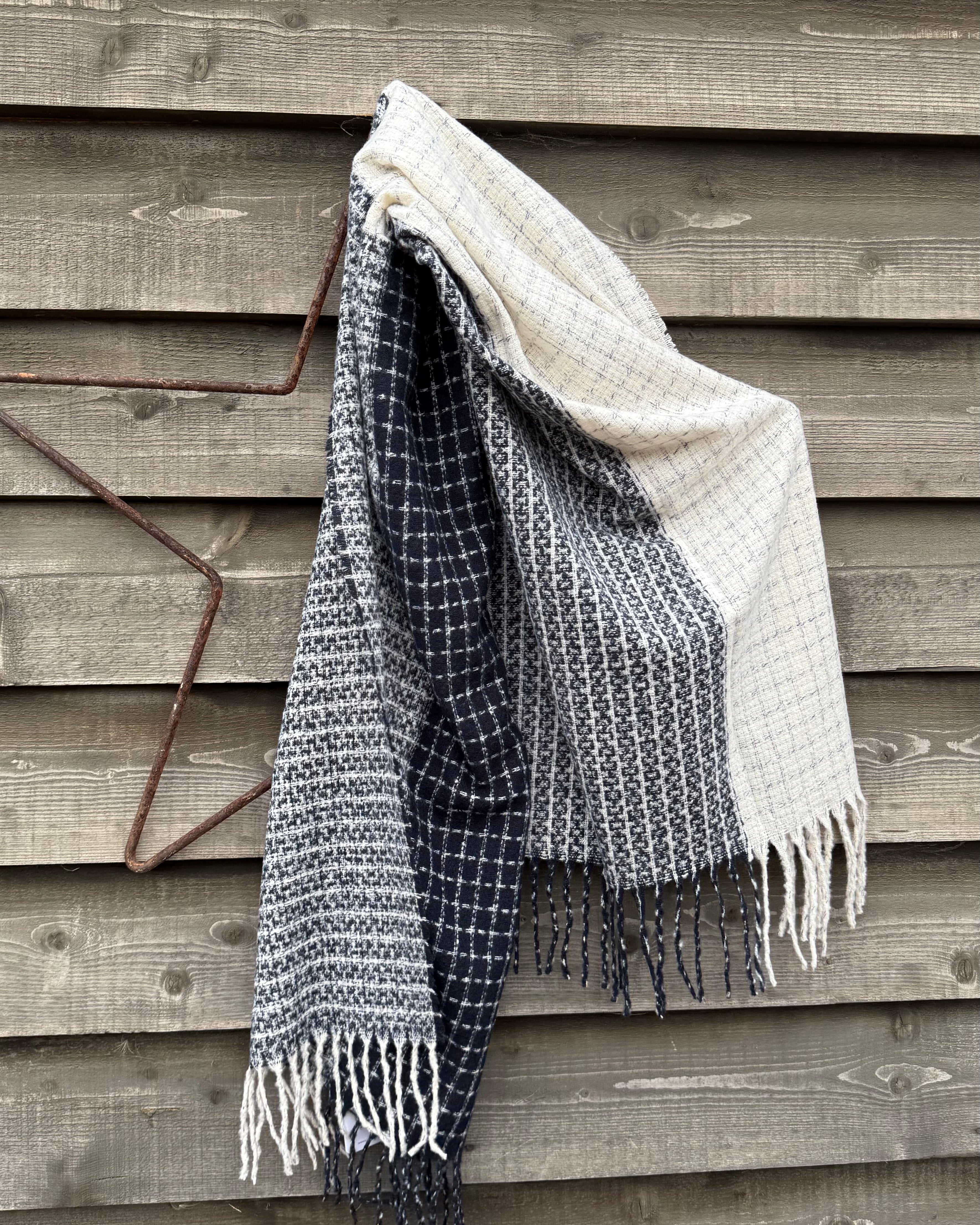 Textured blanket with fringes draped over a wooden surface