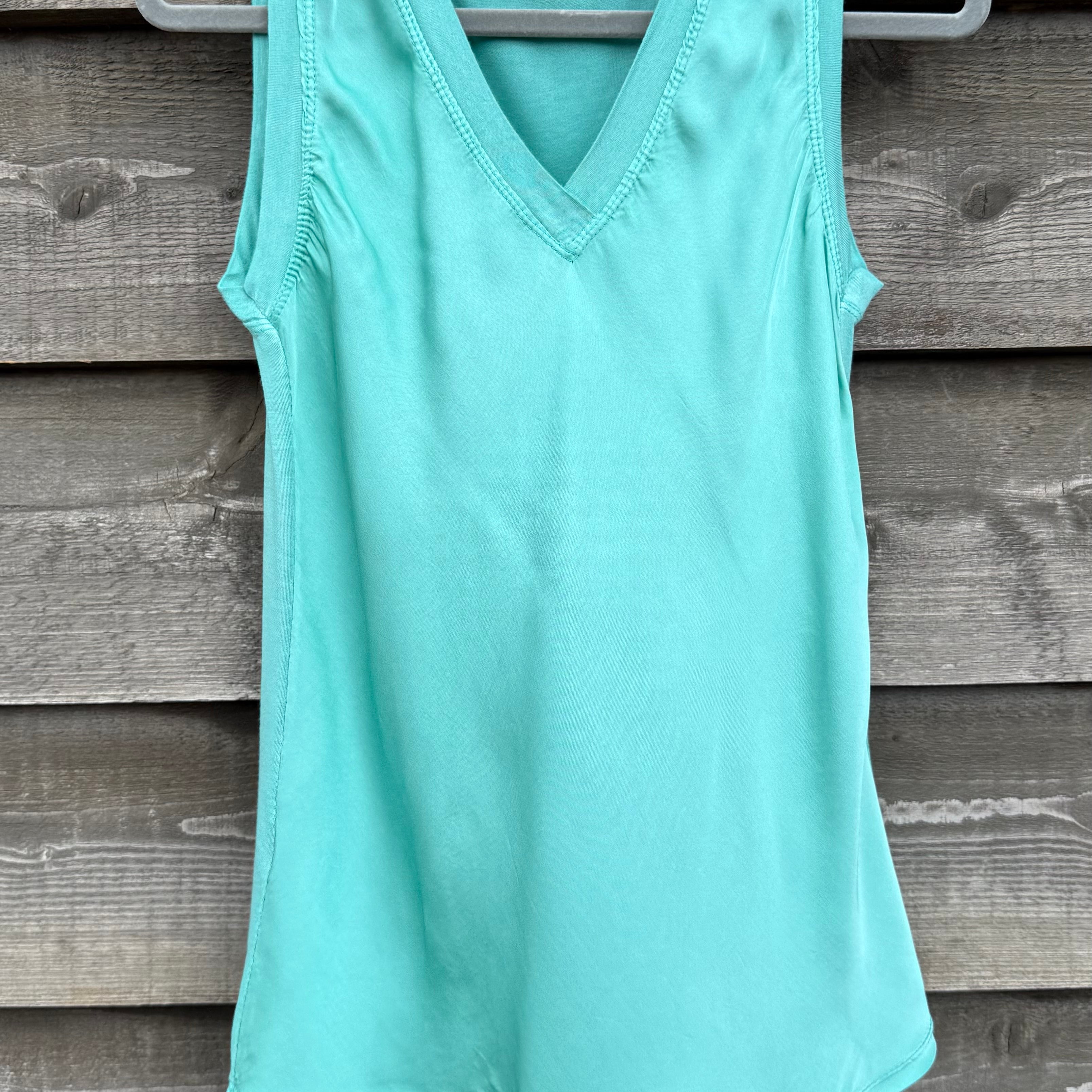 Mint green tank top on a hanger against a wooden background
