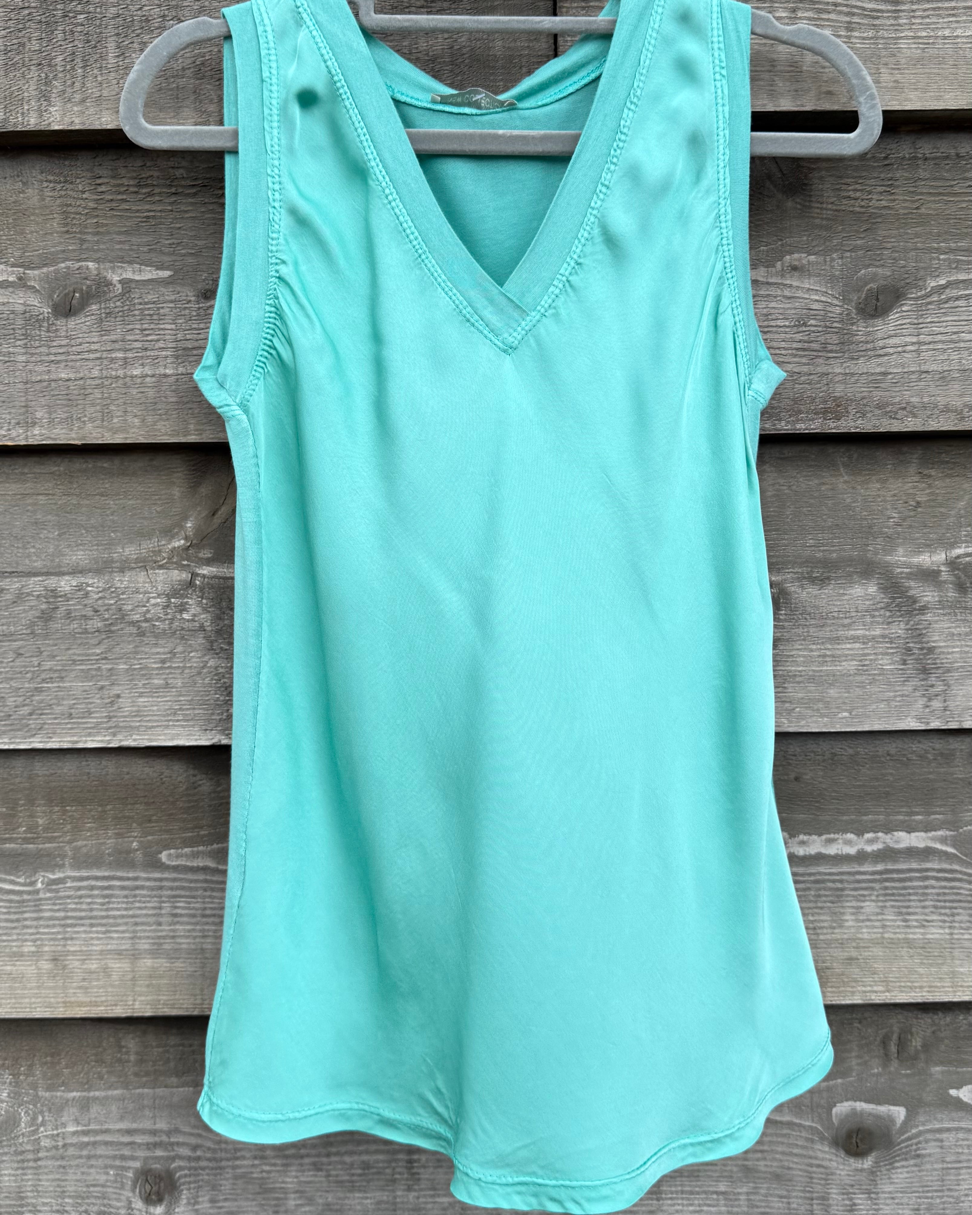 Mint green tank top on a hanger against a wooden background
