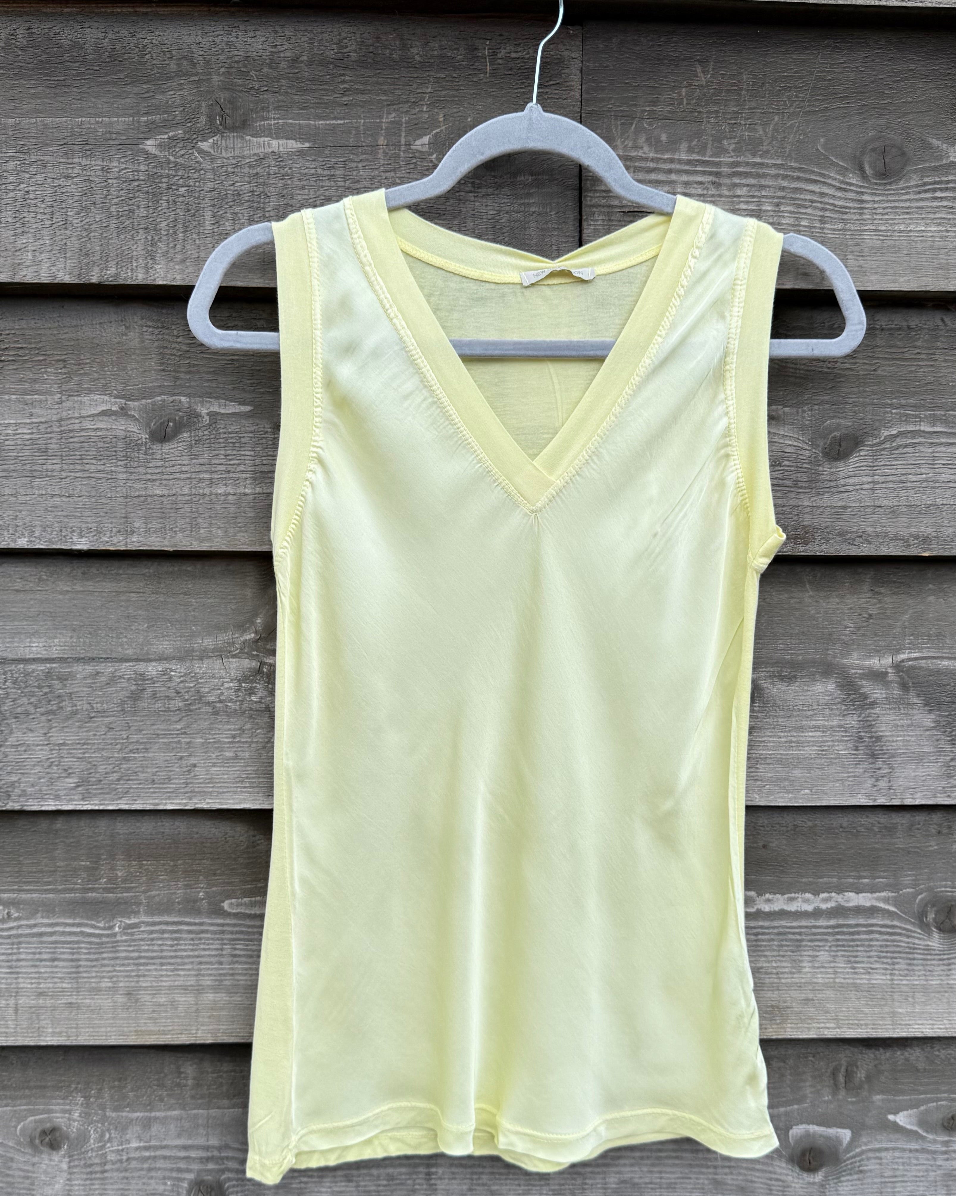 Light yellow tank top hanging on a wooden wall