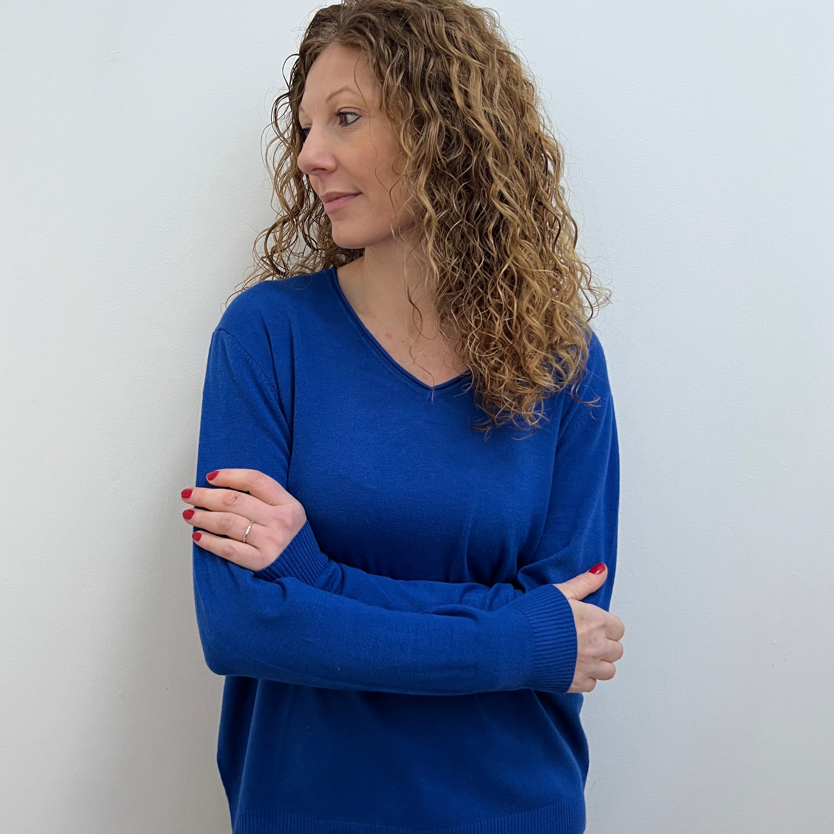 A woman wearing a blue V-neck jumper and blue jeans.