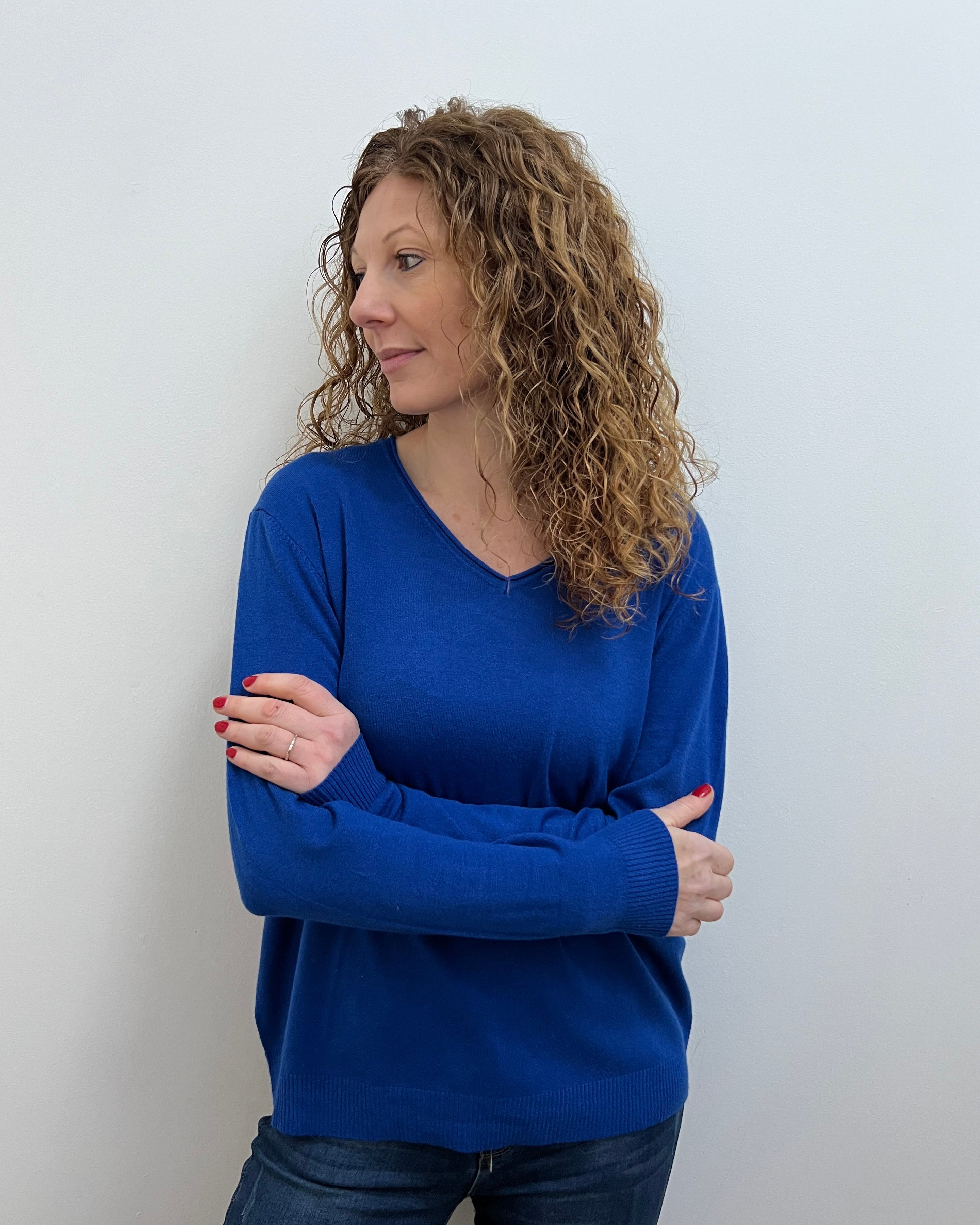 A woman wearing a blue V-neck jumper and blue jeans.