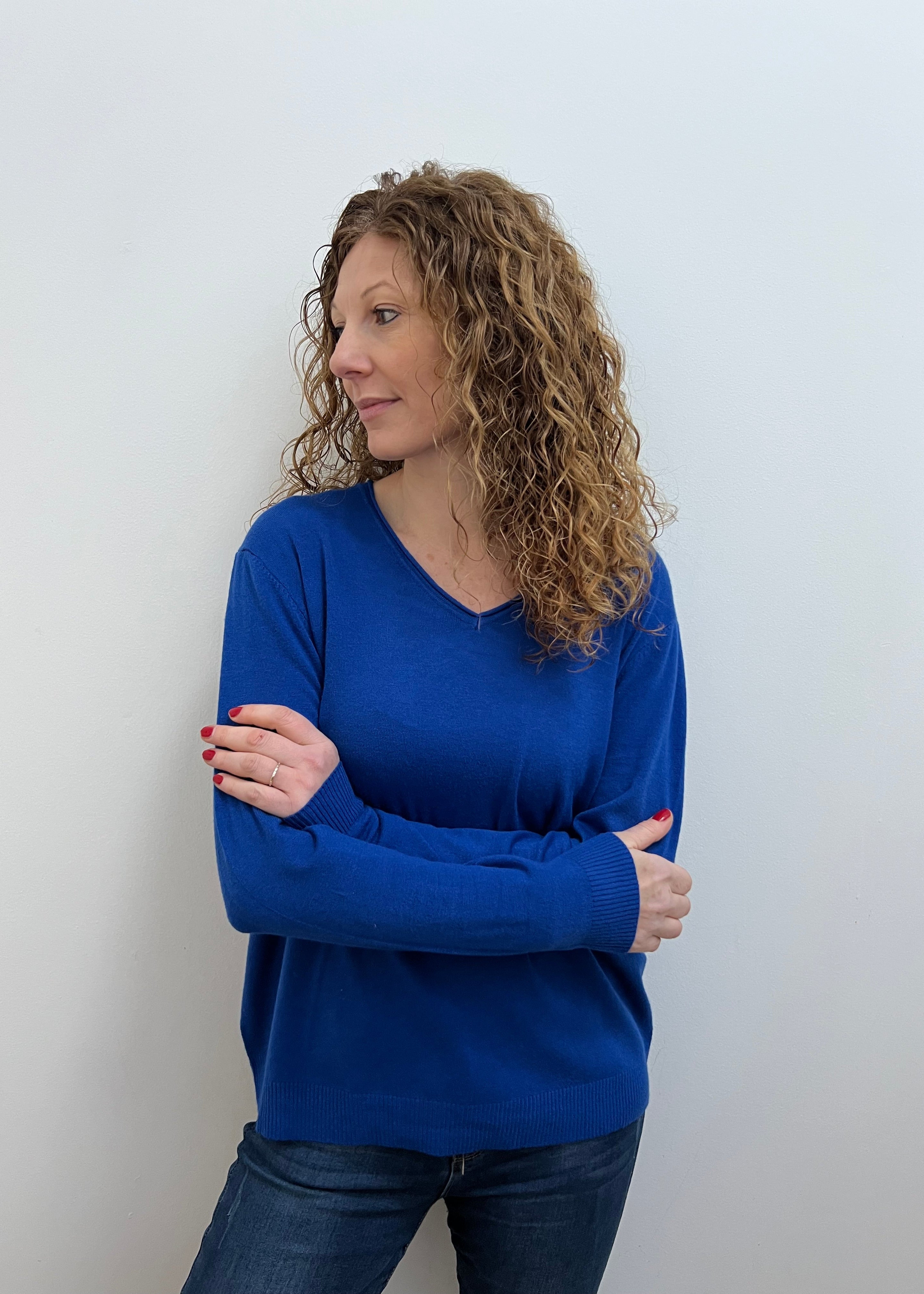 A woman wearing a blue V-neck jumper and blue jeans.
