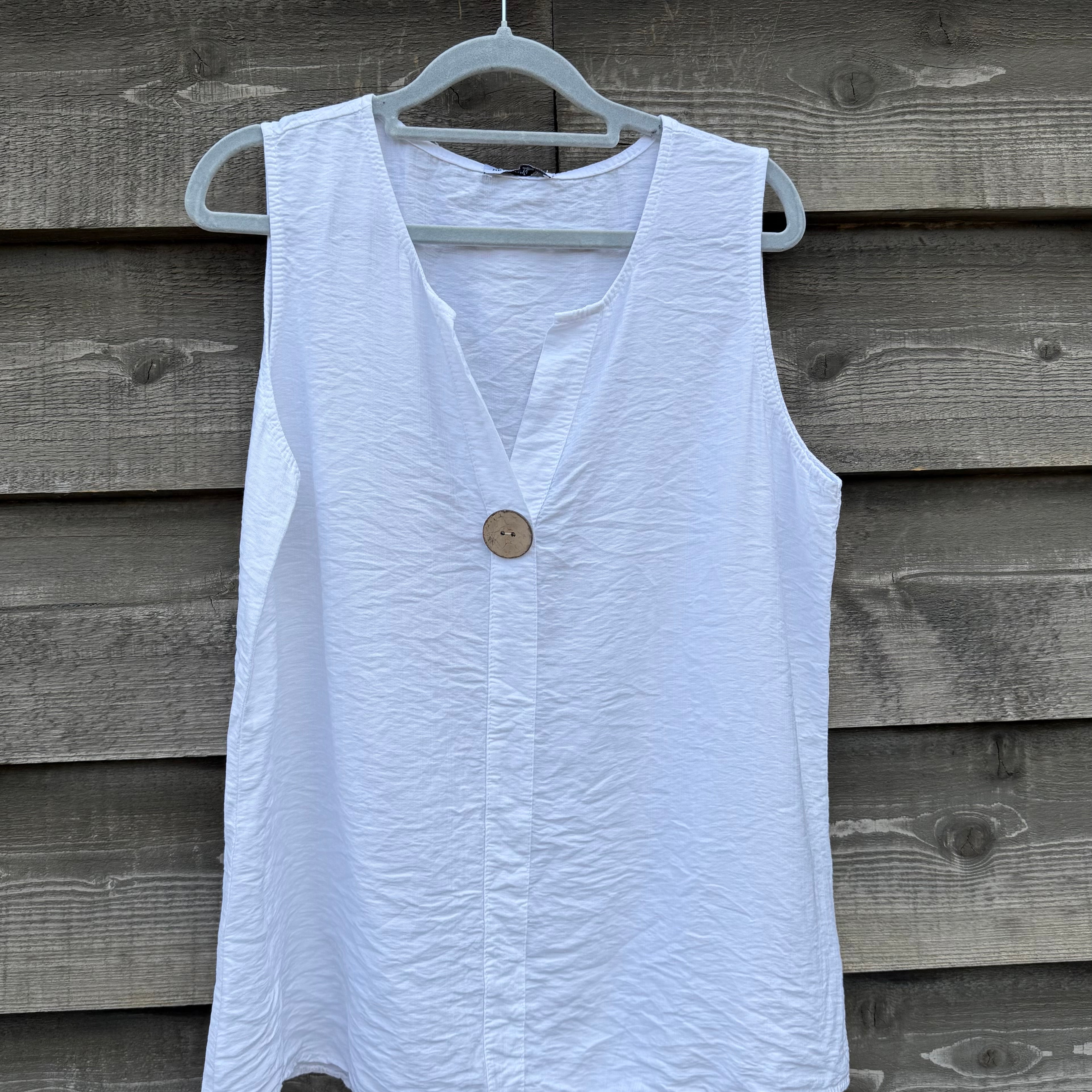 White sleeveless top with a button on a wooden background