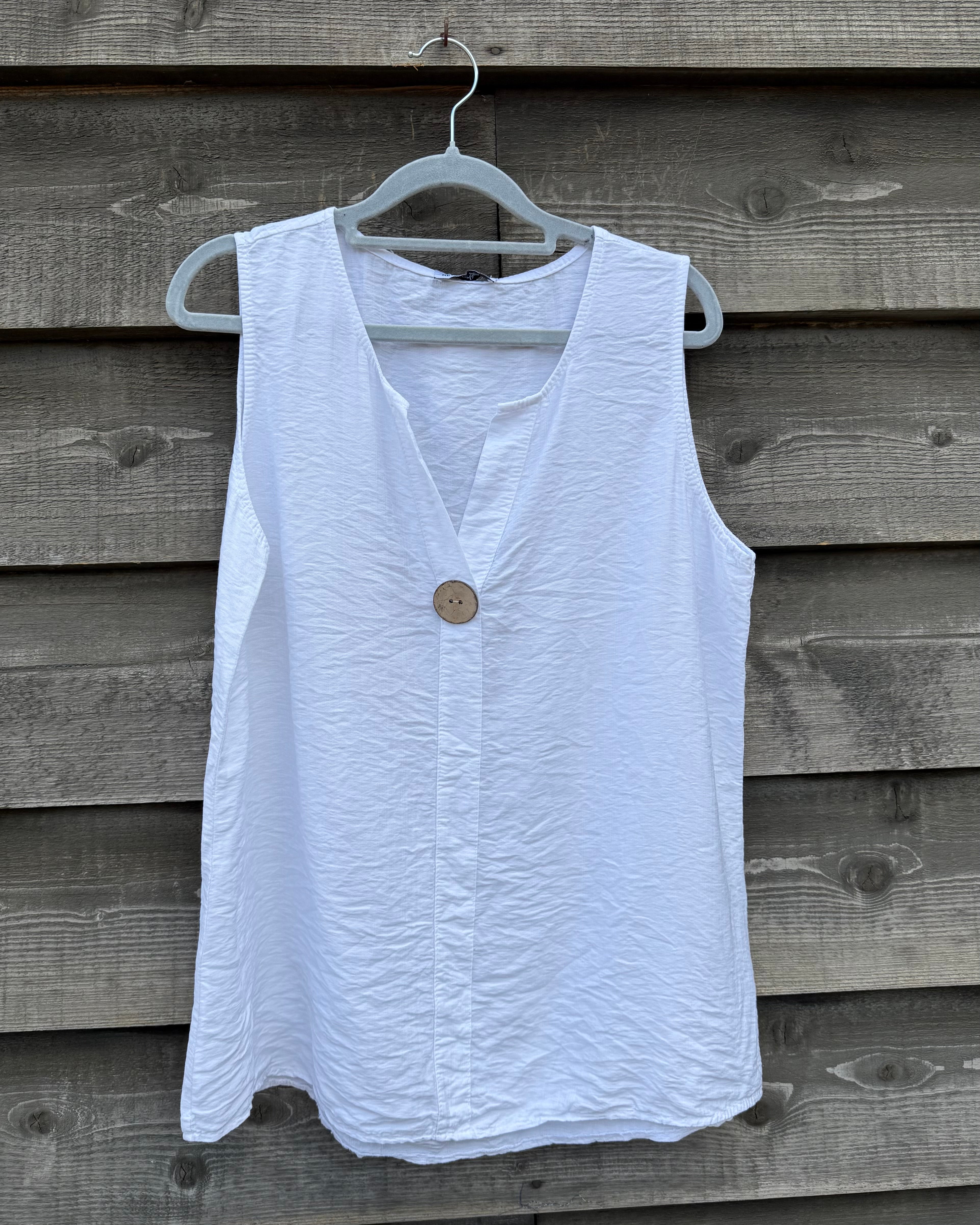 White sleeveless top with a button on a wooden background