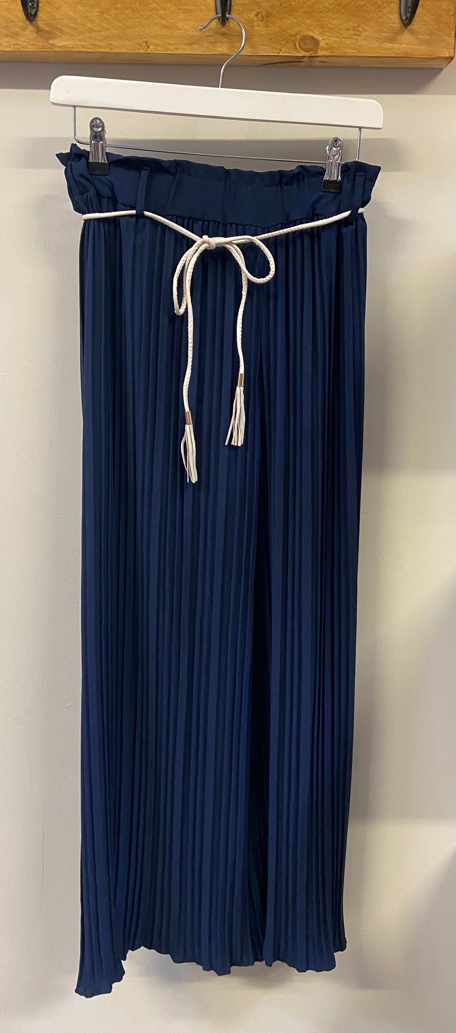 A person wearing yellow pleated trousers with a denim jacket and white shoes.