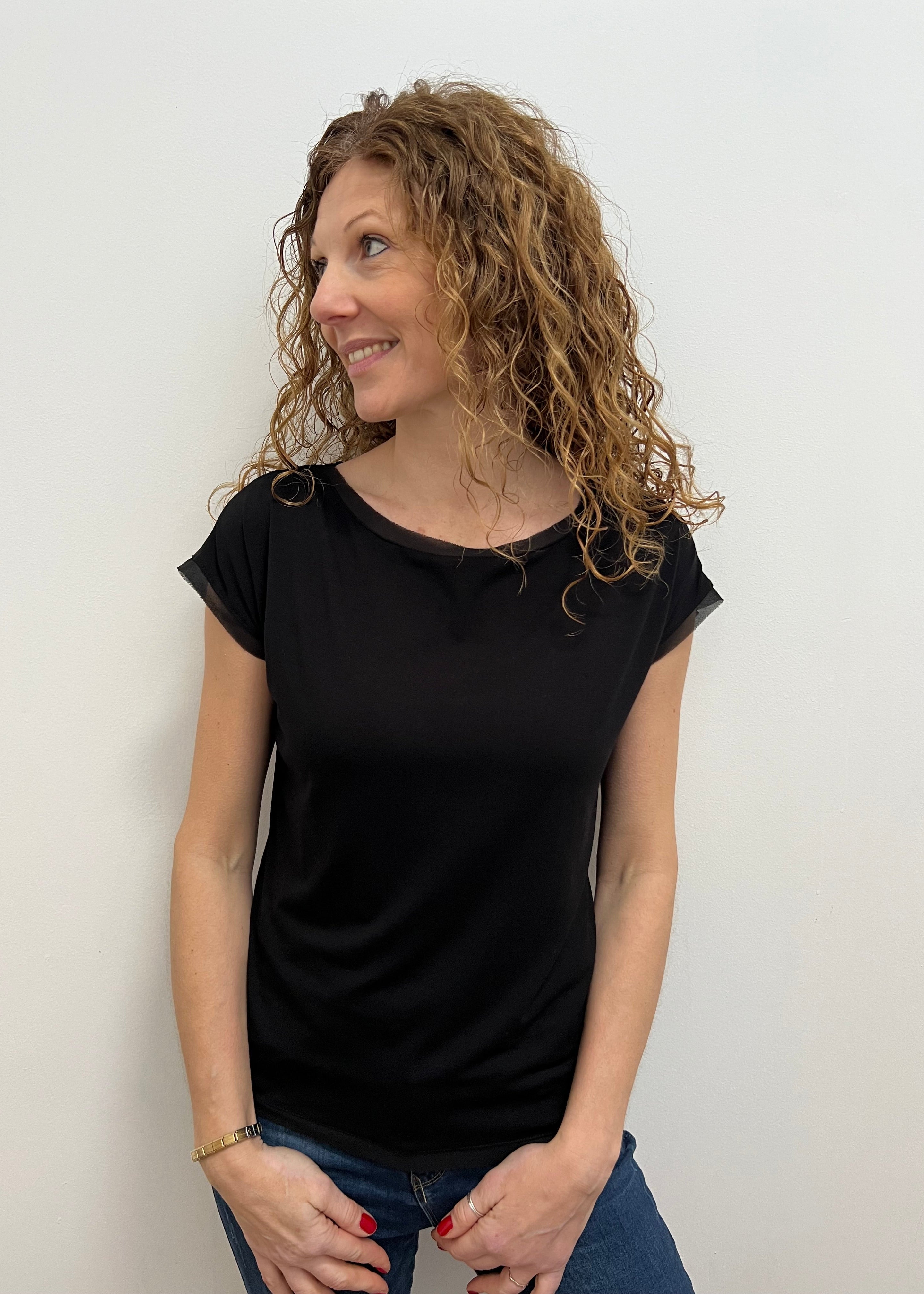 Woman wearing a black t-shirt against a plain background