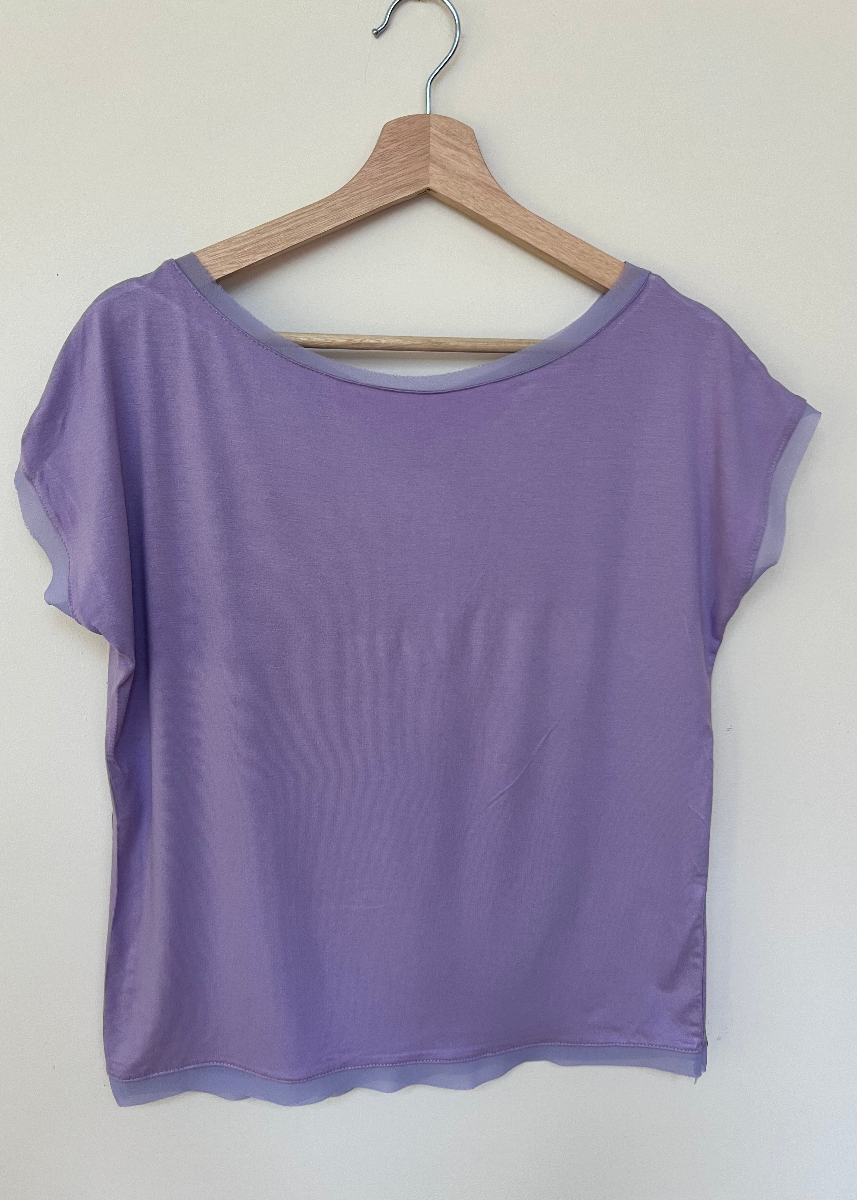 A woman wearing a white short-sleeved t-shirt with a slightly fitted style, standing against a plain background.