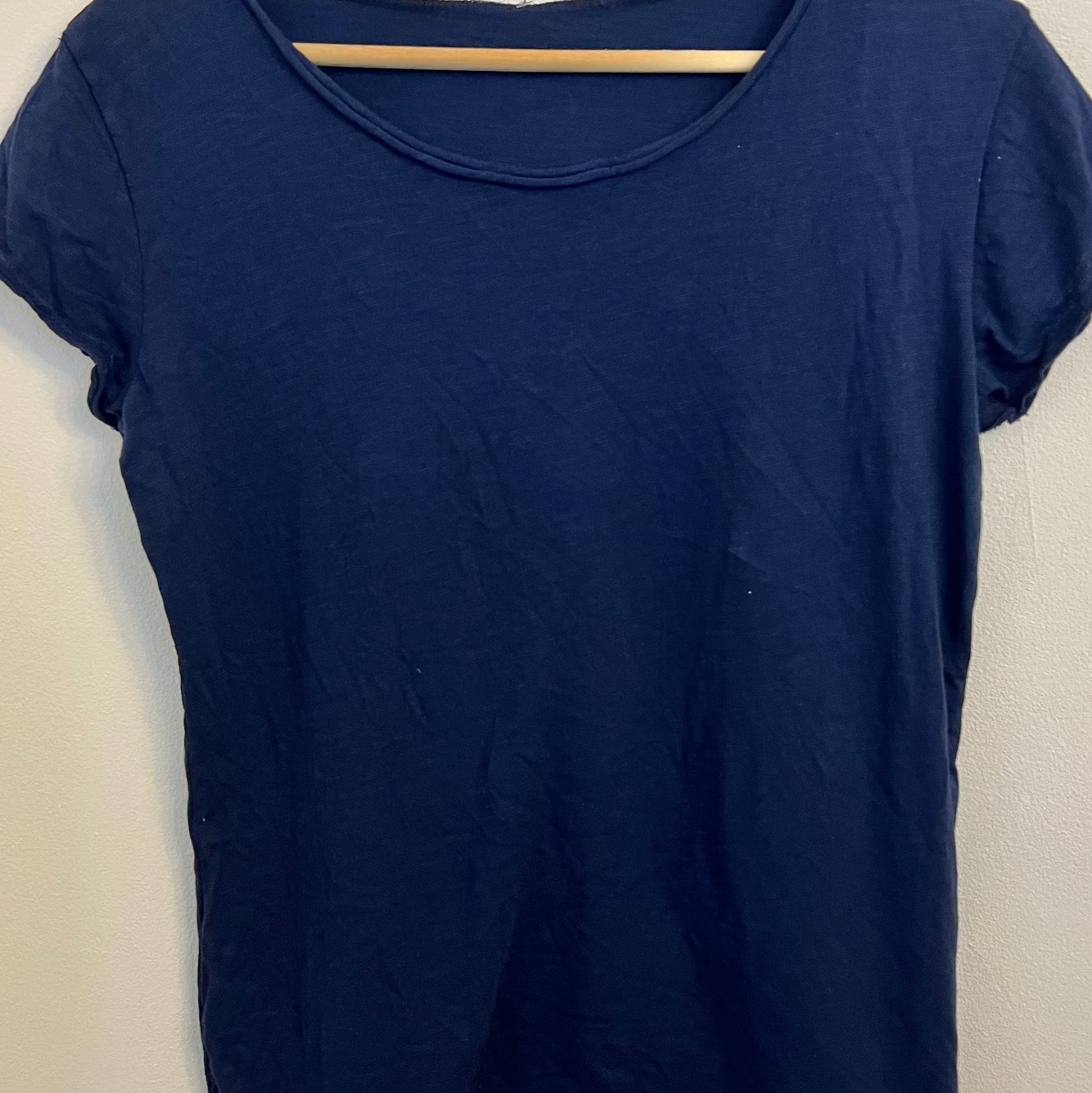 Navy blue t-shirt on a wooden hanger against a white background