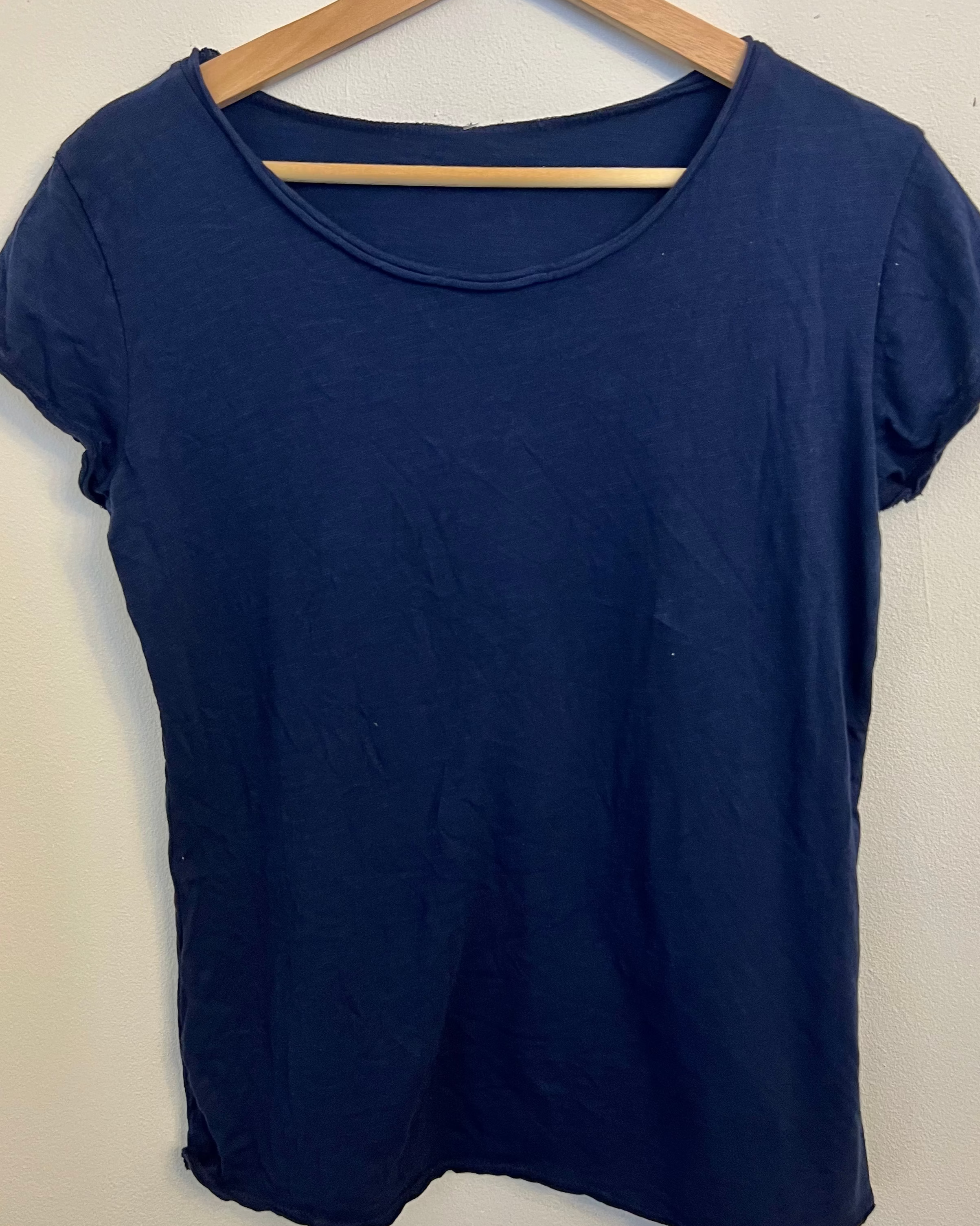 Navy blue t-shirt on a wooden hanger against a white background
