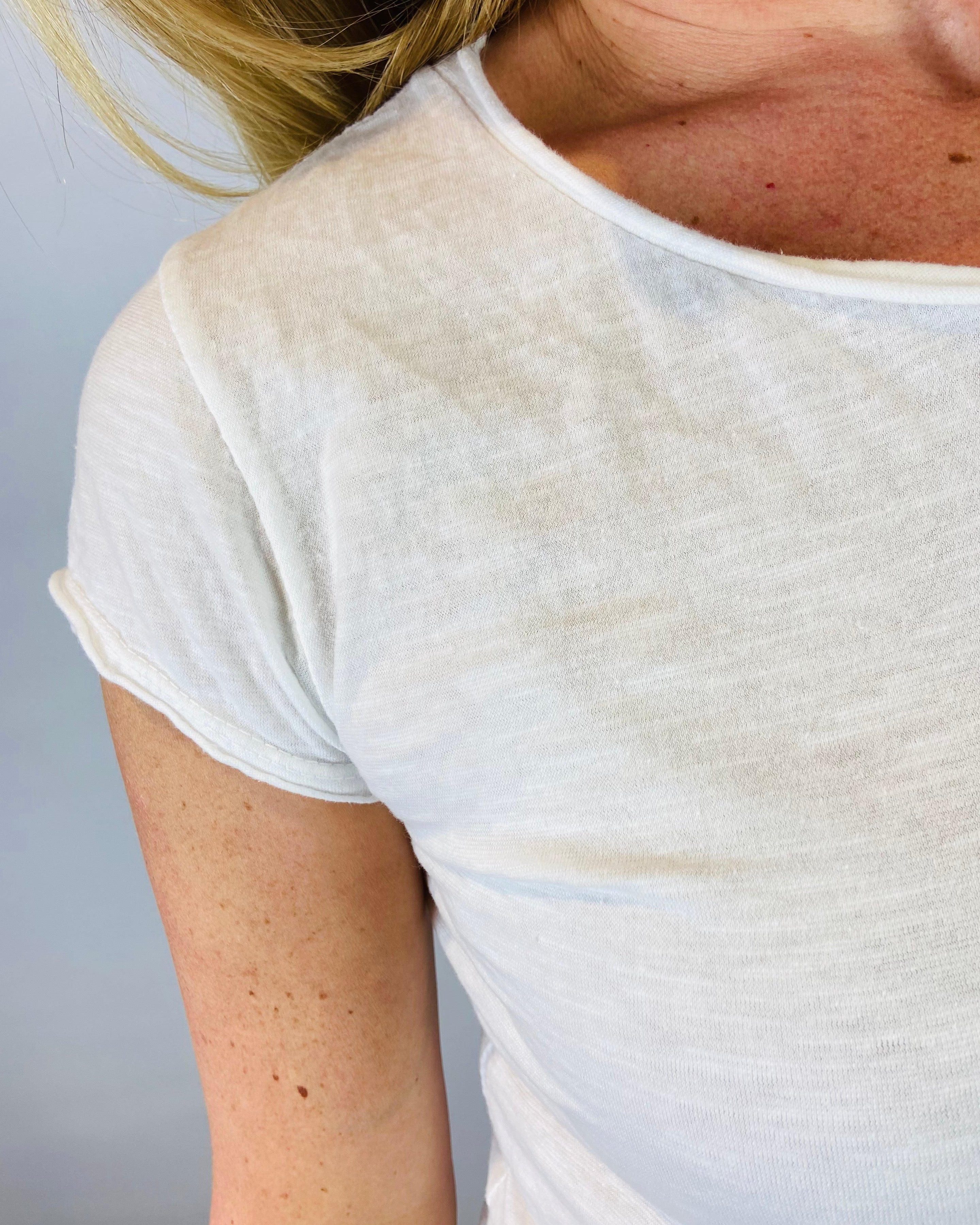 Close-up of a person wearing a white t-shirt against a plain background