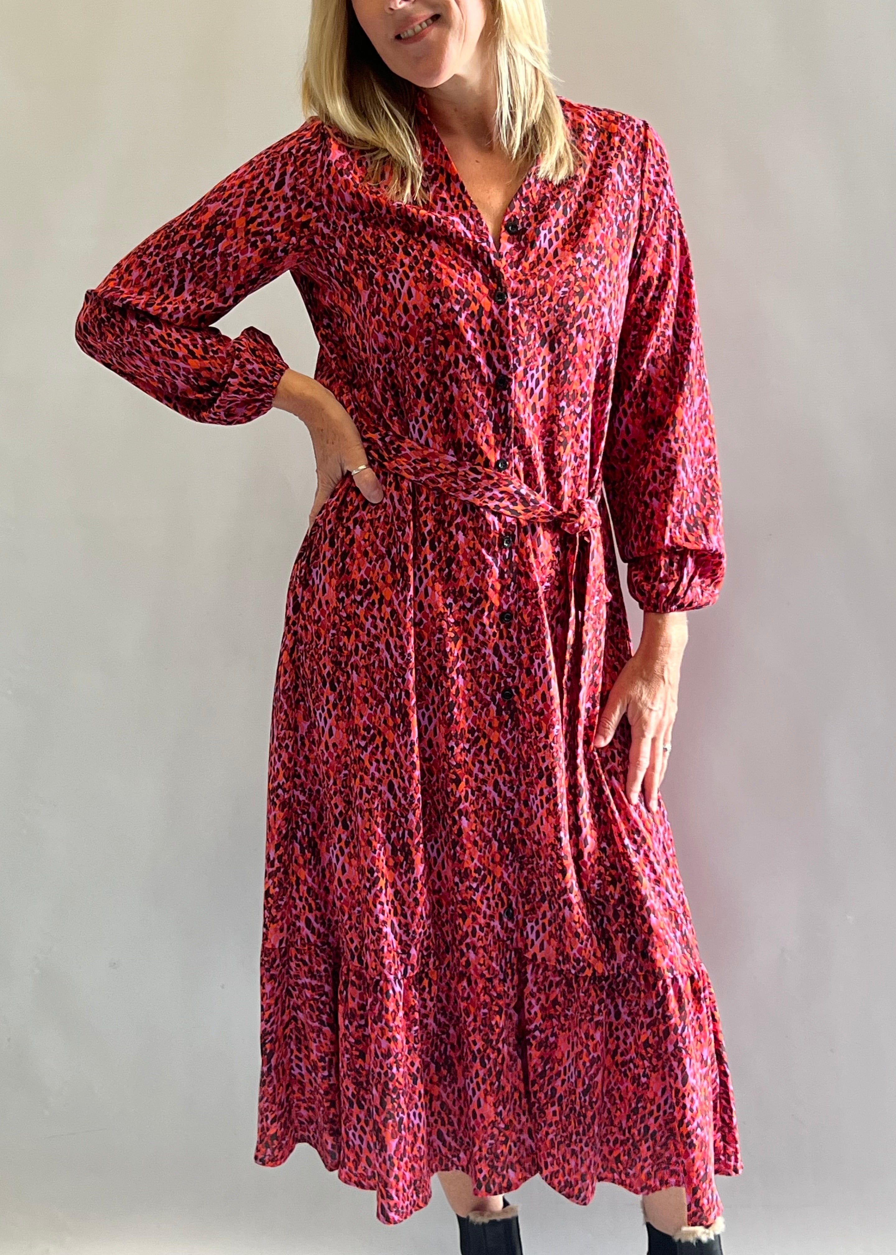 Lady wearing shirt dress with blue and green print, styled with white trainers.