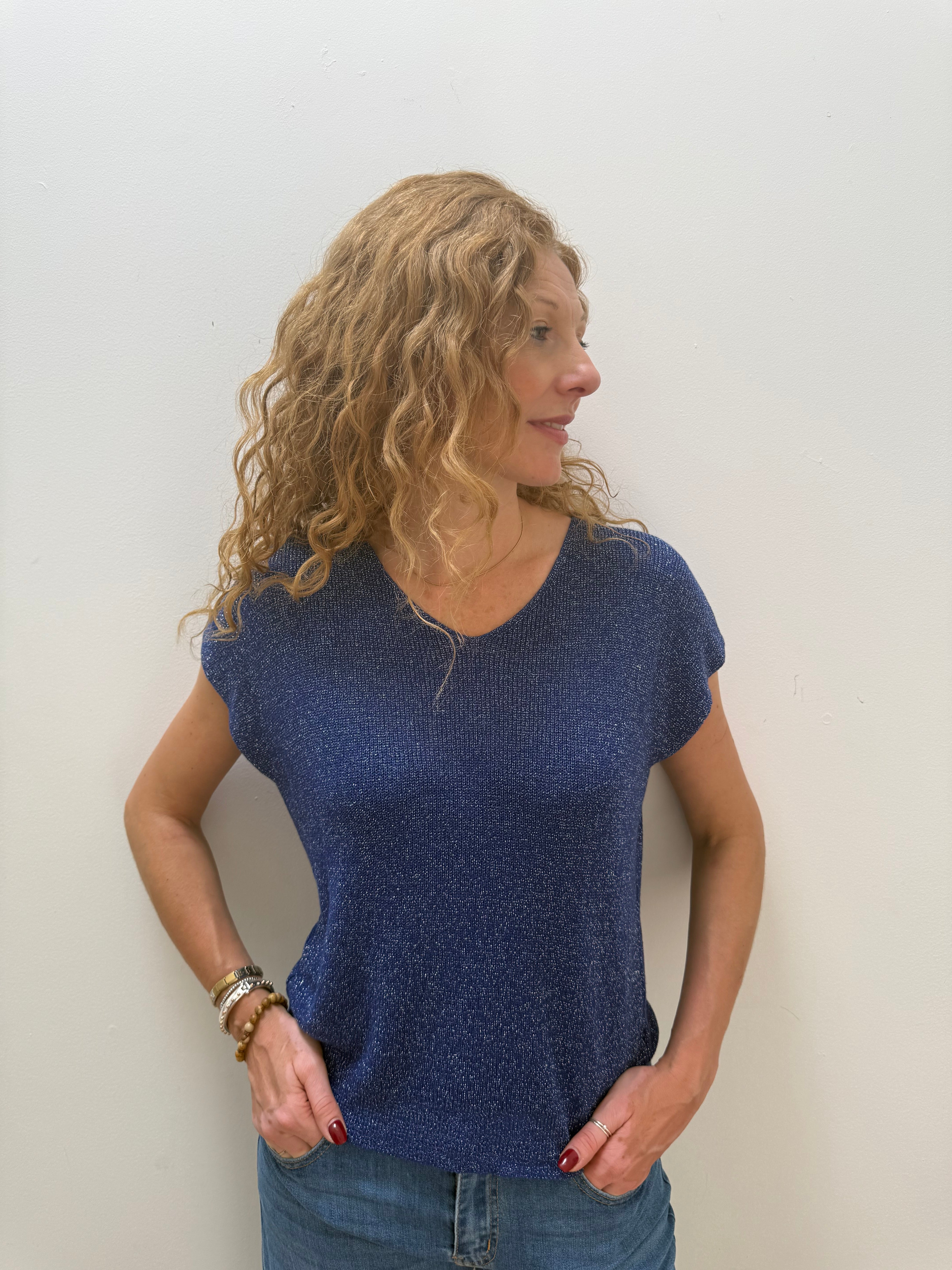 Woman wearing a blue top and jeans against a white background